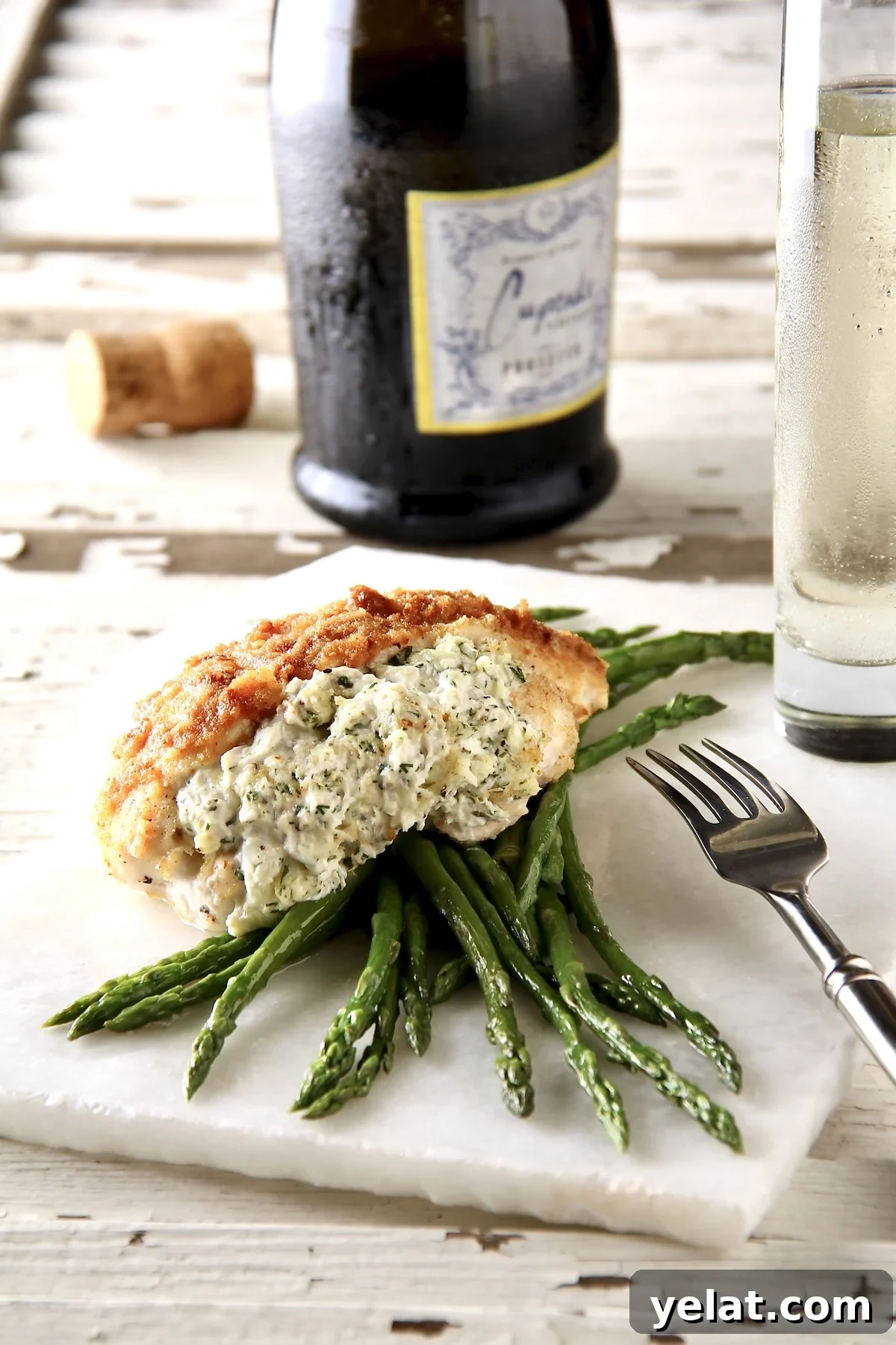 One serving of Crab-Stuffed Chicken Breasts over asparagus on thin piece of marble.