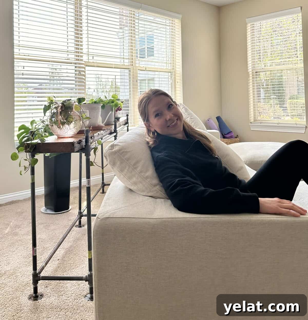 My 7th Avenue Sofa Review: Modular, PFAS-Free Upholstery 6 A woman sitting on a PFAS-free sofa from 7th Avenue, with small plants behind her.