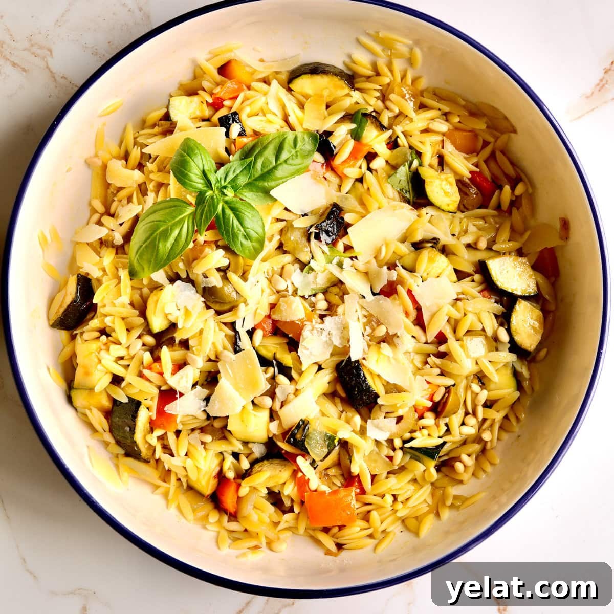 Orzo pasta with roasted vegetables and parmesan in a bowl.