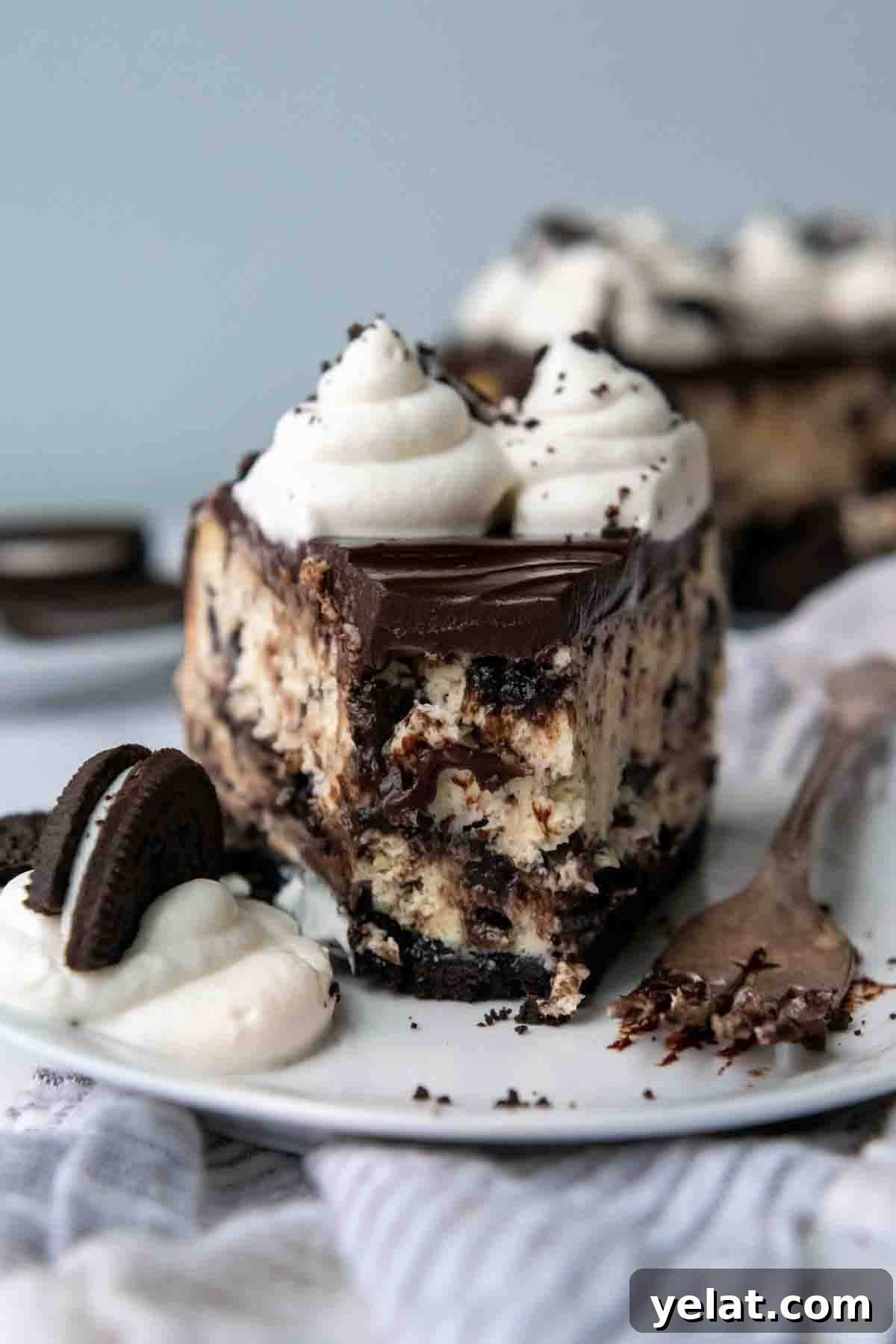 Ultra-Cream Gluten-Free Oreo Cheesecake Recipe 2 a slice of gluten free oreo cheesecake with a bite taken out on a white plate.
