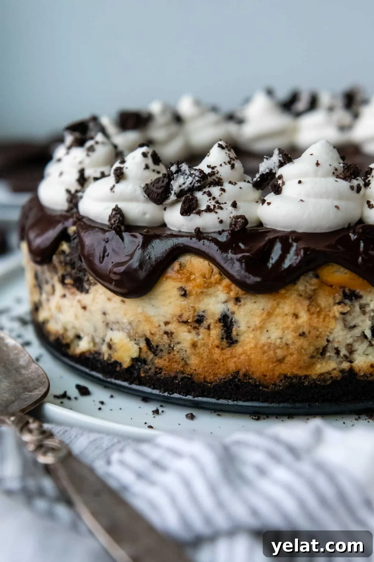 Ultra-Cream Gluten-Free Oreo Cheesecake Recipe 9 an uncut gluten free oreo cheesecake with ganache and whipped cream on top.