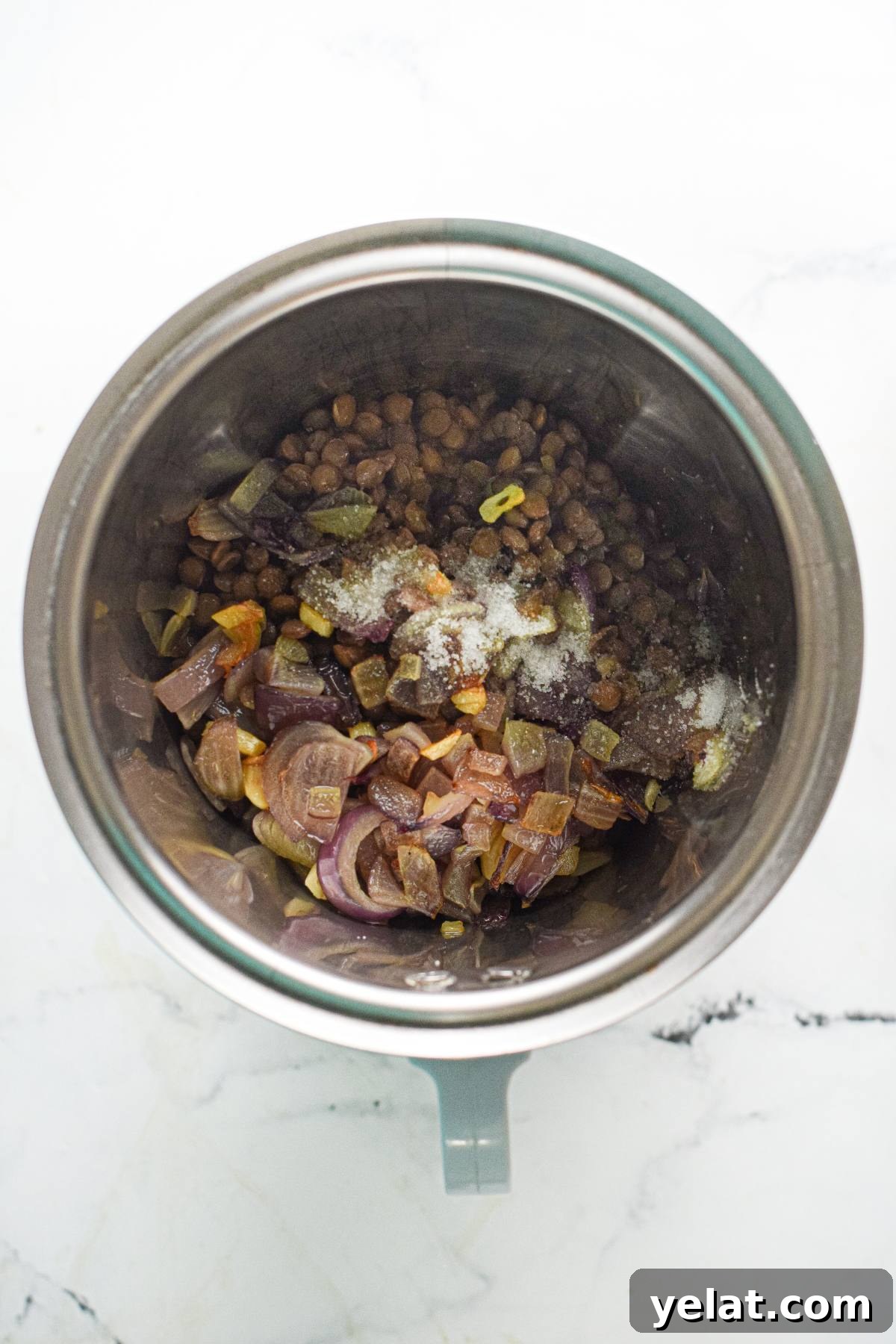 Air Fryer Meatballs in Marinara Sauce: Quick Homemade Recipe 14 Chopped vegetables and seasonings in a metal pot, ready to be blended for an easy vegan meatball recipe, on a white marble surface.