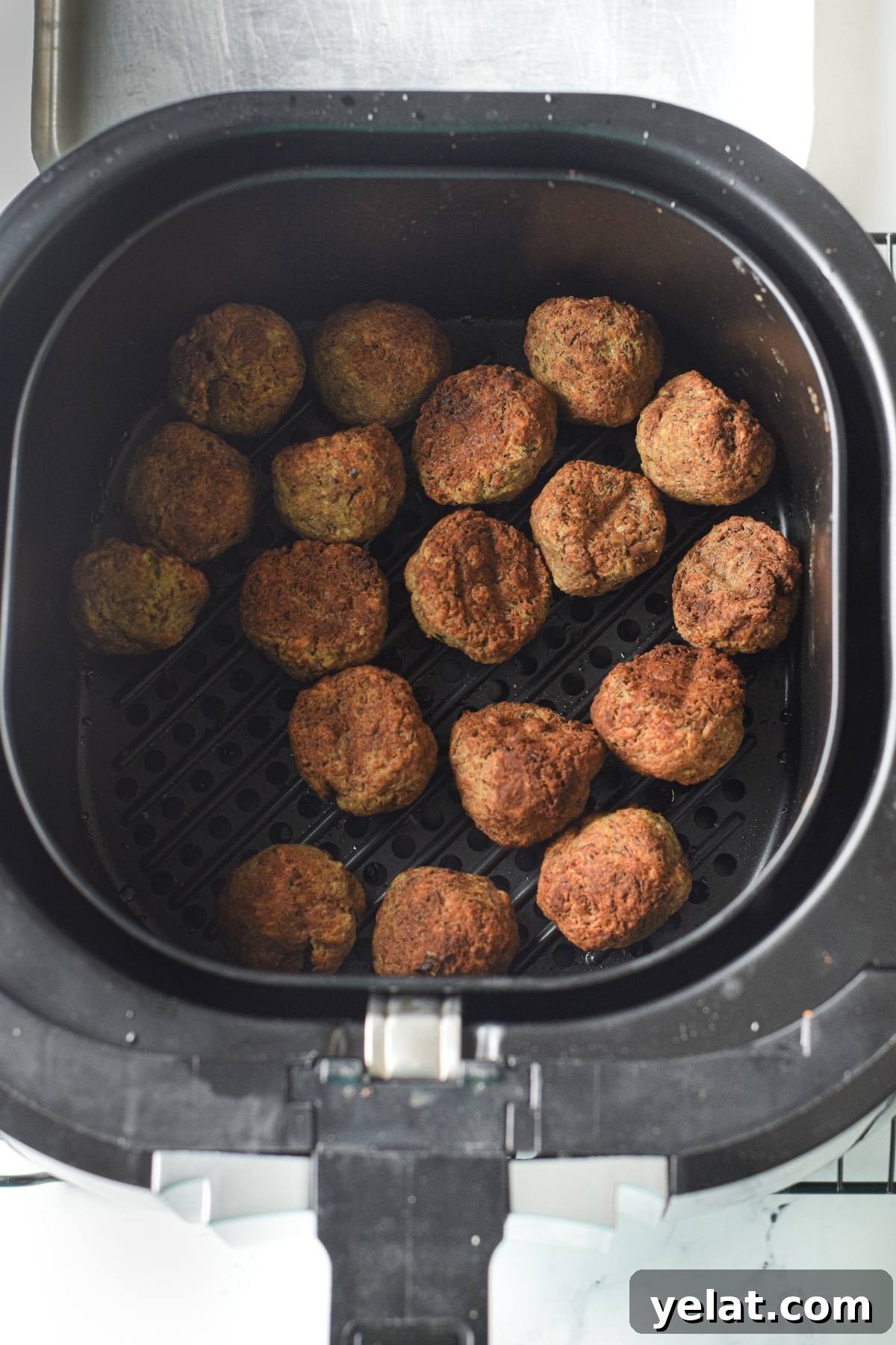 Air Fryer Meatballs in Marinara Sauce: Quick Homemade Recipe 17 Air fryer basket filled with golden-brown falafel balls, similar to gluten free air fryer meatballs, perfectly arranged on the perforated tray.