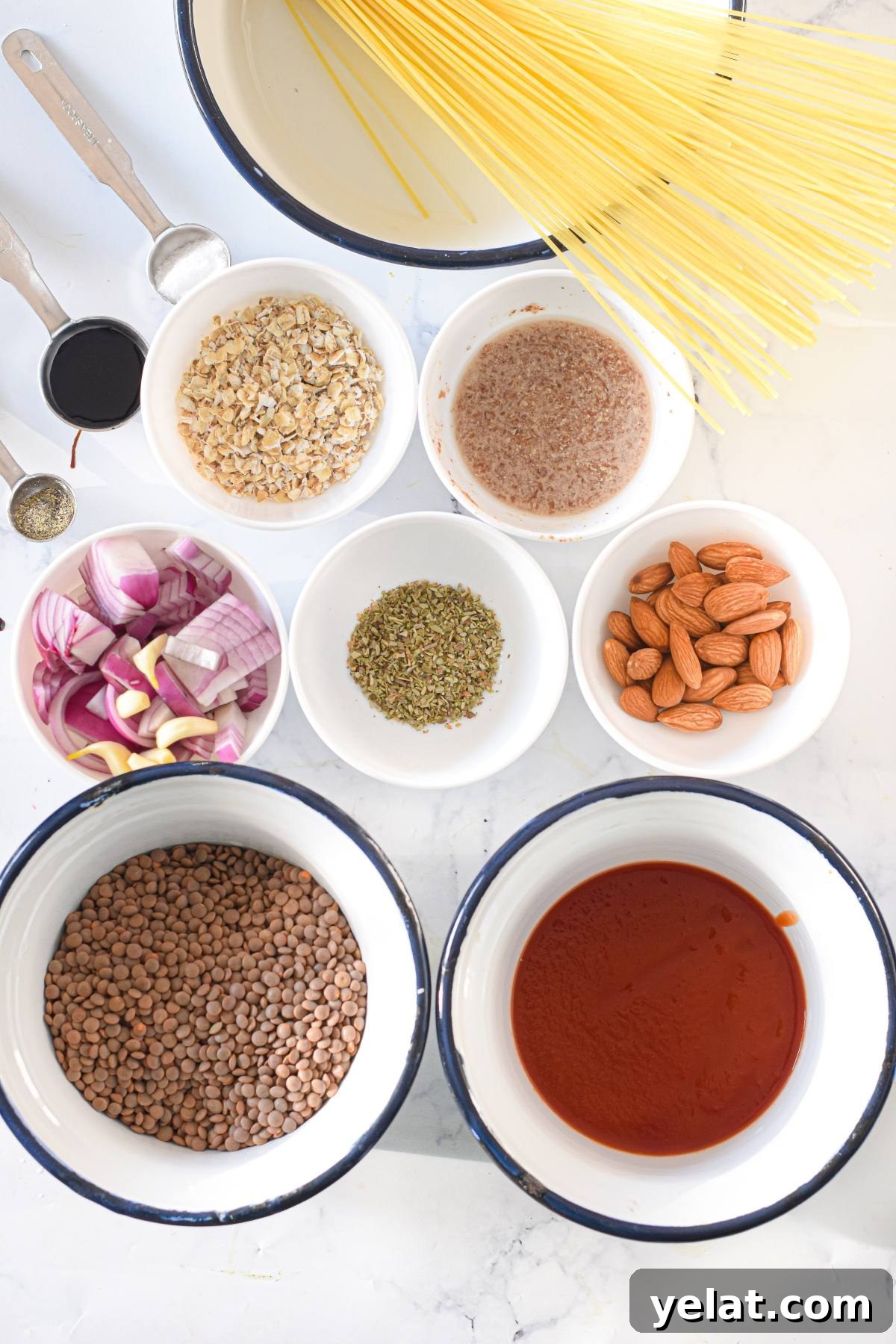 Air Fryer Meatballs in Marinara Sauce: Quick Homemade Recipe 5 Overhead view of uncooked spaghetti, lentils, tomato sauce, almonds, spices, onions, oats, and measuring spoons—perfect ingredients for a Vegan meatball recipe or Gluten free air fryer meatballs.