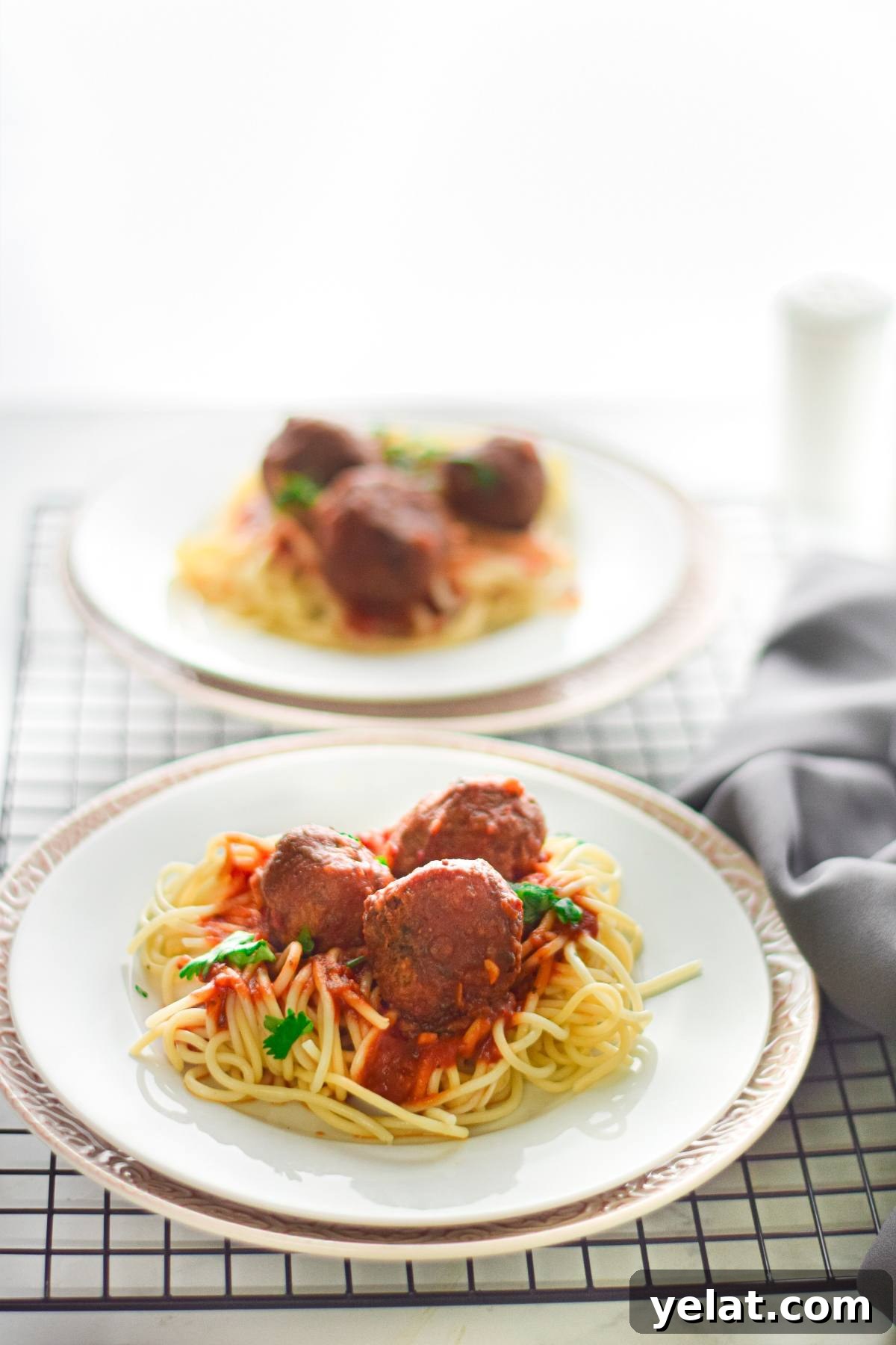 Air Fryer Meatballs in Marinara Sauce: Quick Homemade Recipe 7 A plate of spaghetti with tomato sauce and easy vegan meatballs, garnished with parsley, sits on a table.