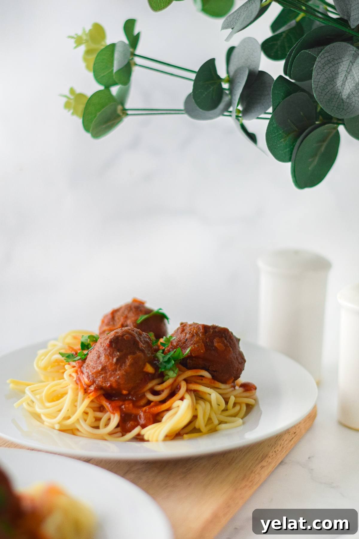 Air Fryer Meatballs in Marinara Sauce: Quick Homemade Recipe 10 A plate of spaghetti with Gluten Free Air Fryer Meatballs in tomato sauce, garnished with parsley, served on a wooden board.
