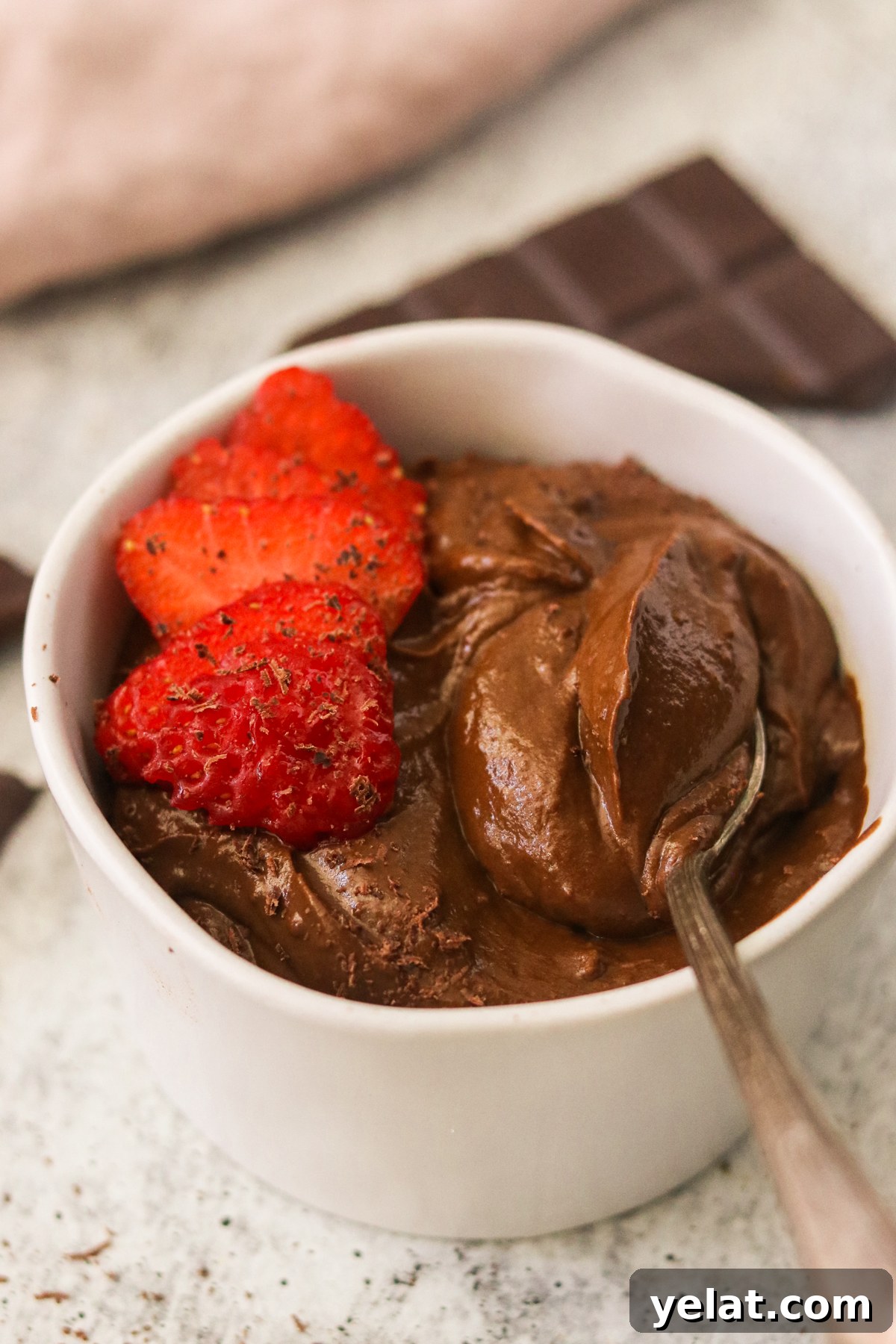 Creamy Avocado Chocolate Pudding Even Picky Eaters Love 2 A small white bowl with sweet potato avocado chocolate pudding, topped with sliced strawberries and shaved chocolate