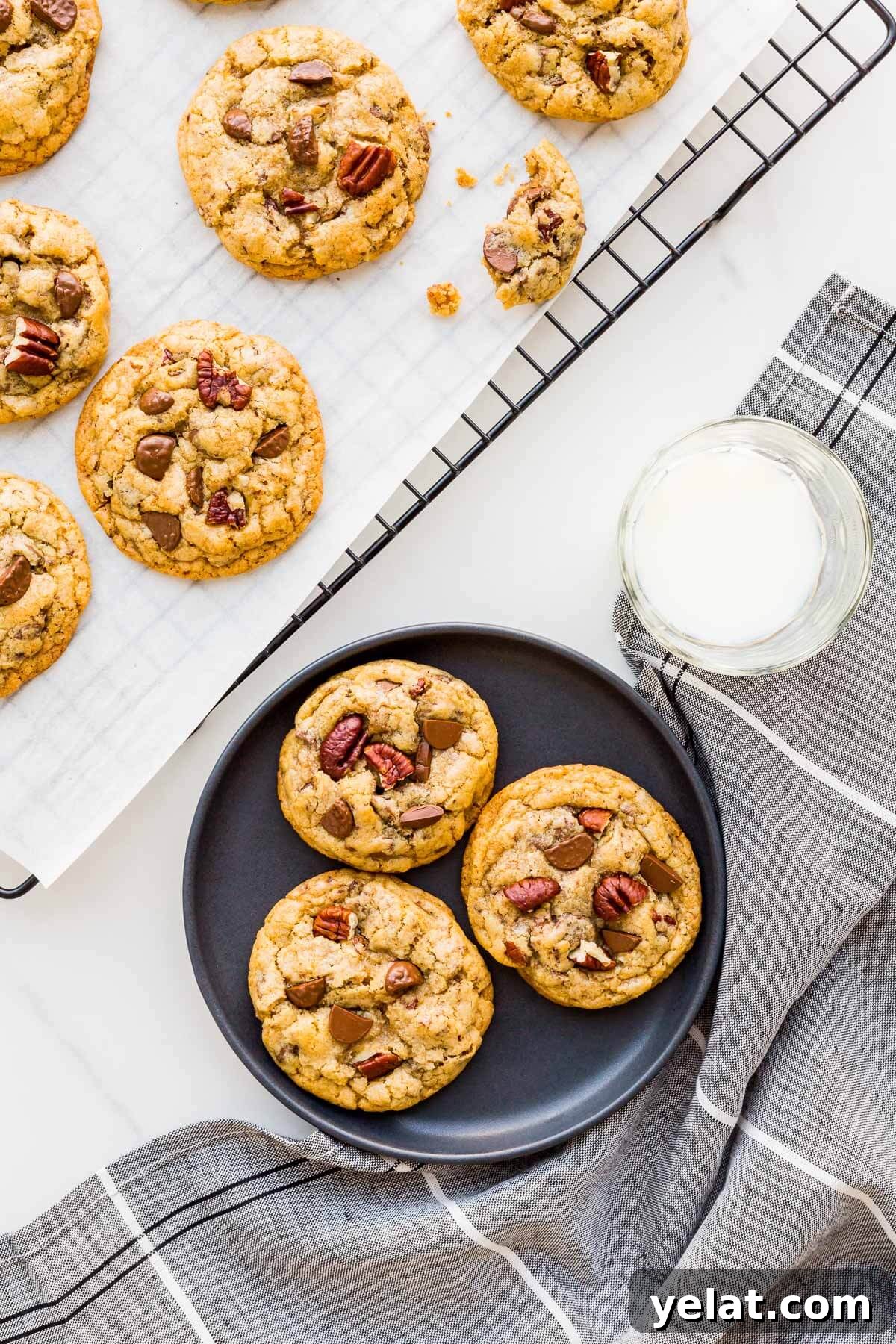 Chewy Chocolate Chip Pecan Cookies Recipe 2 Milk chocolate chip cookies with pecans being served on a black plate from a cooling rack.