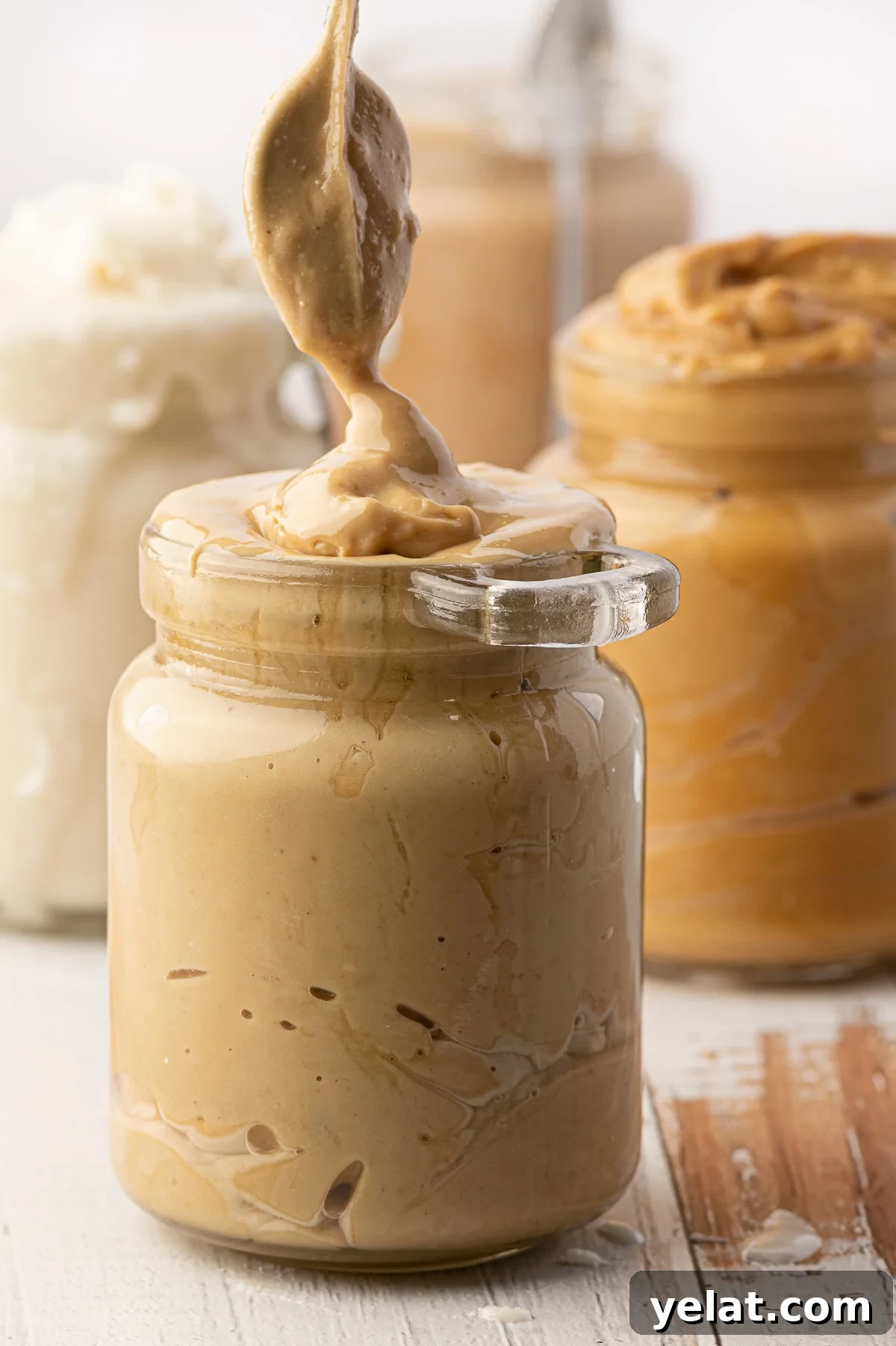 Low-Carb Pantry Essentials for Baking: Flour Substitutes & Staples 16 Jars of nut butters (peanut, cashew, coconut) on a rustic wooden background.