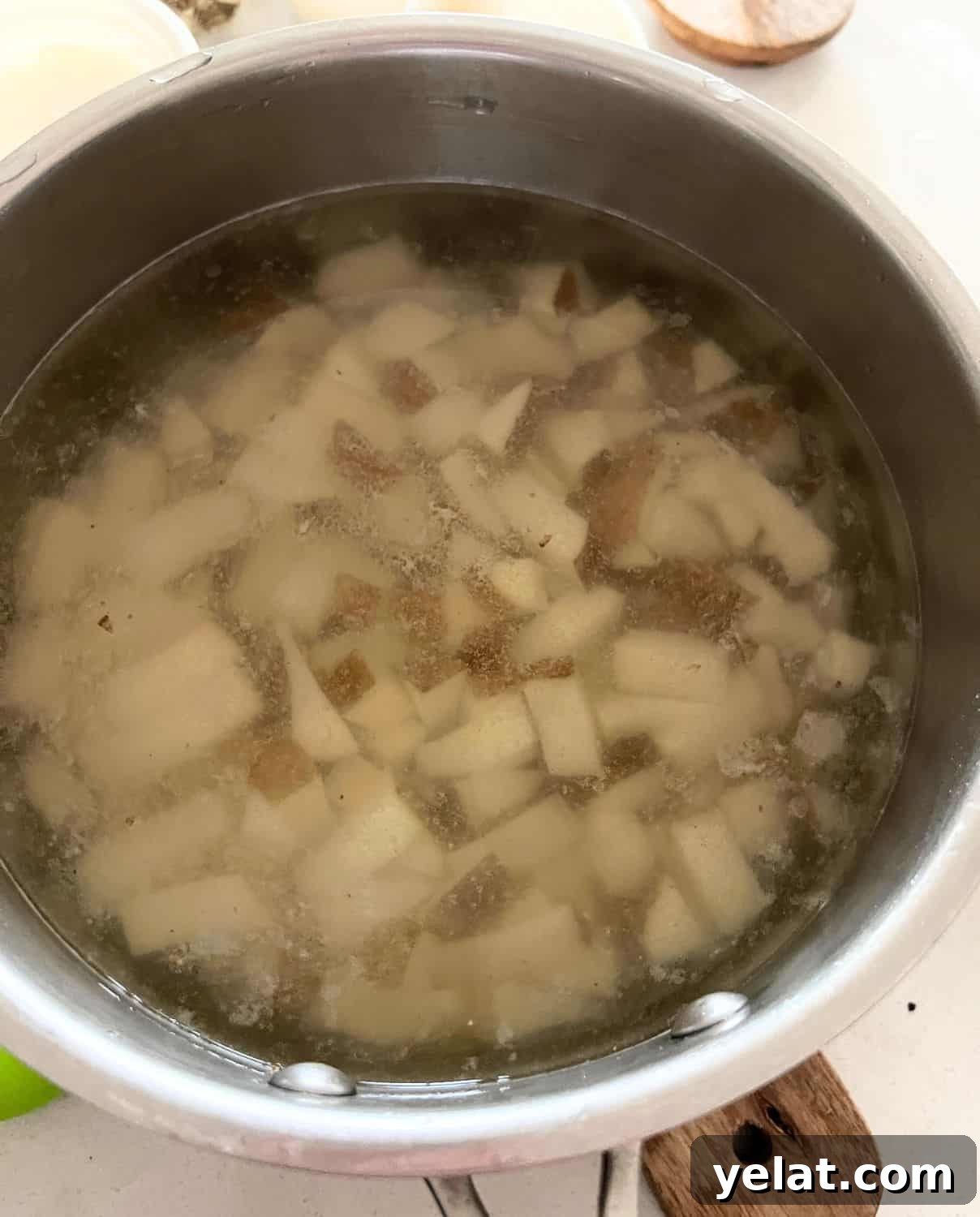 Creamy Mashed Potatoes Made with Greek Yogurt 4 Potatoes and garlic in a sauce pan with water.