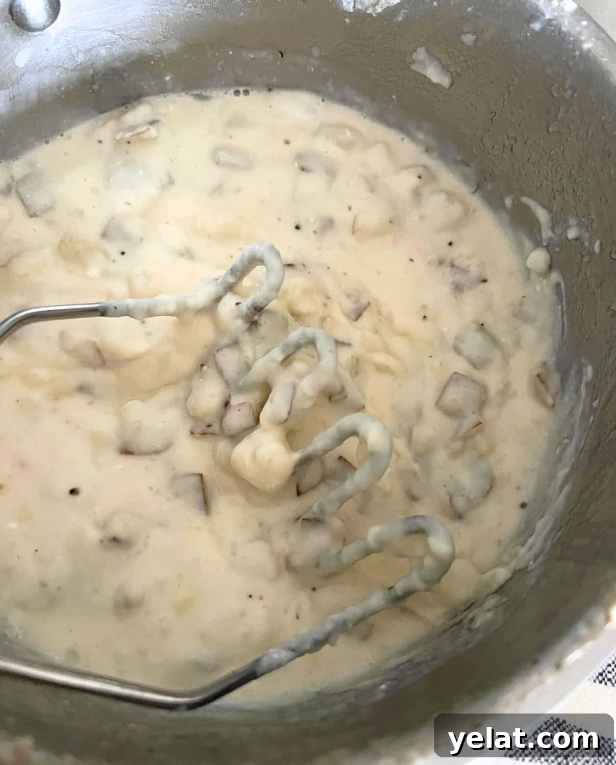 Creamy Mashed Potatoes Made with Greek Yogurt 6 Mashed potatoes with a potato masher in a pot.