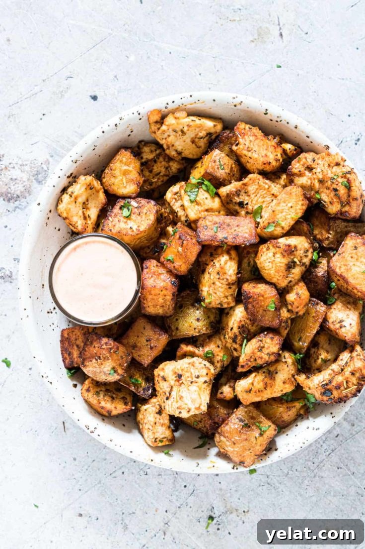 White bowl filled with chicken and potatoes and a small bowl of dipping sauce.