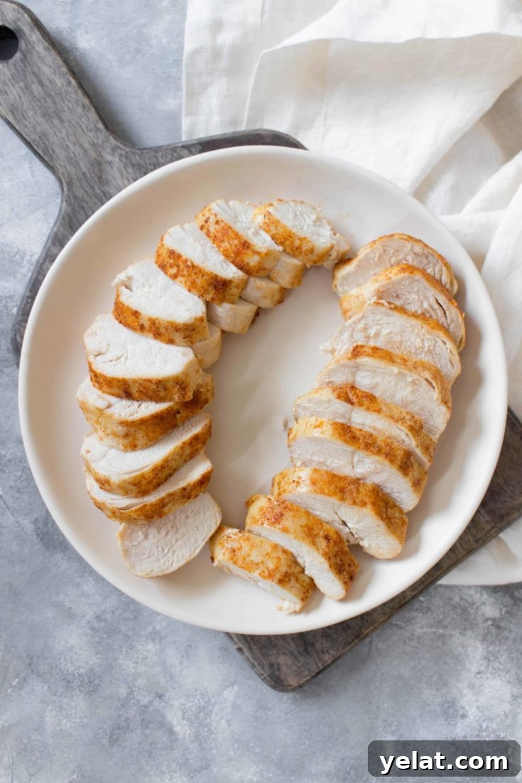 Overhead of sliced chicken breasts fanned out on a white serving platter.