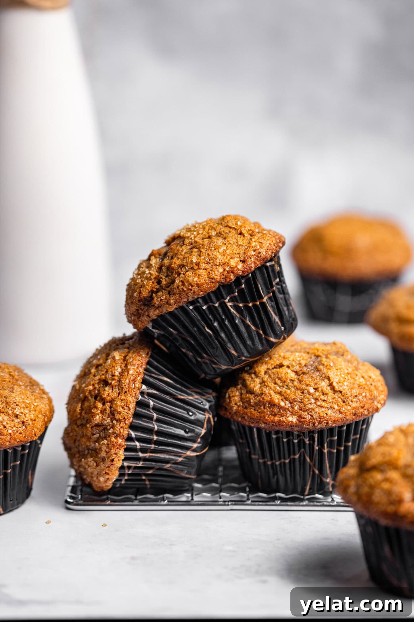 Moist Small-Batch Banana Muffins Recipe for Perfect Breakfast 2 A stack of small batch banana muffins on top of and around a cooling rack.