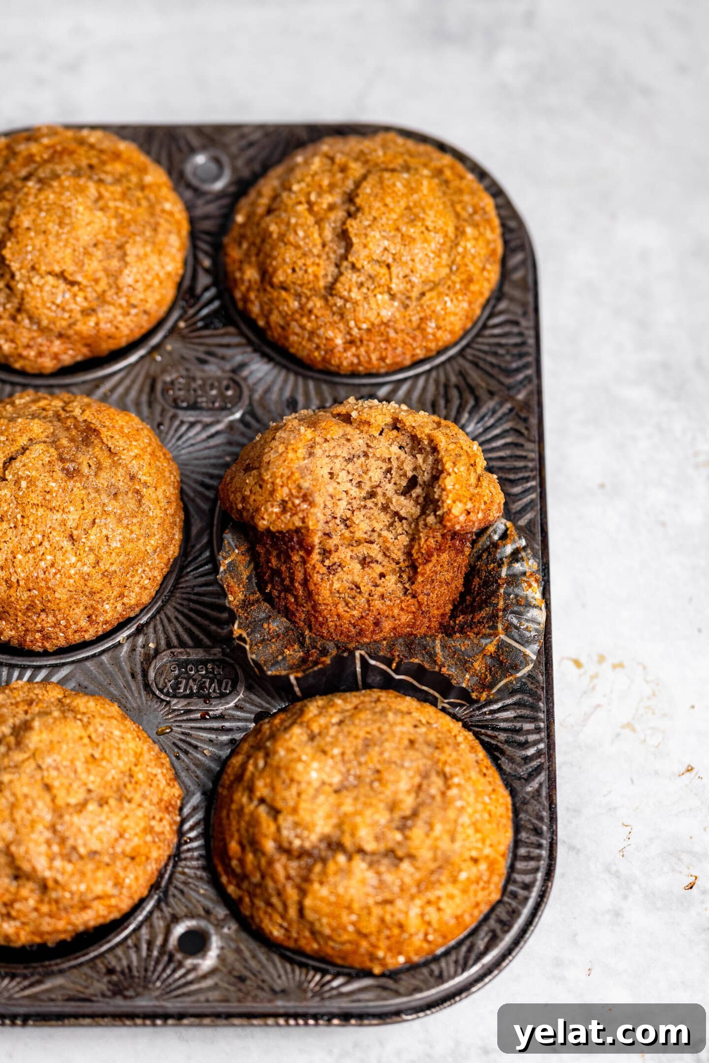 Moist Small-Batch Banana Muffins Recipe for Perfect Breakfast 11 Banana muffins inside a muffin pan with one muffin missing a bite and showing off the interior