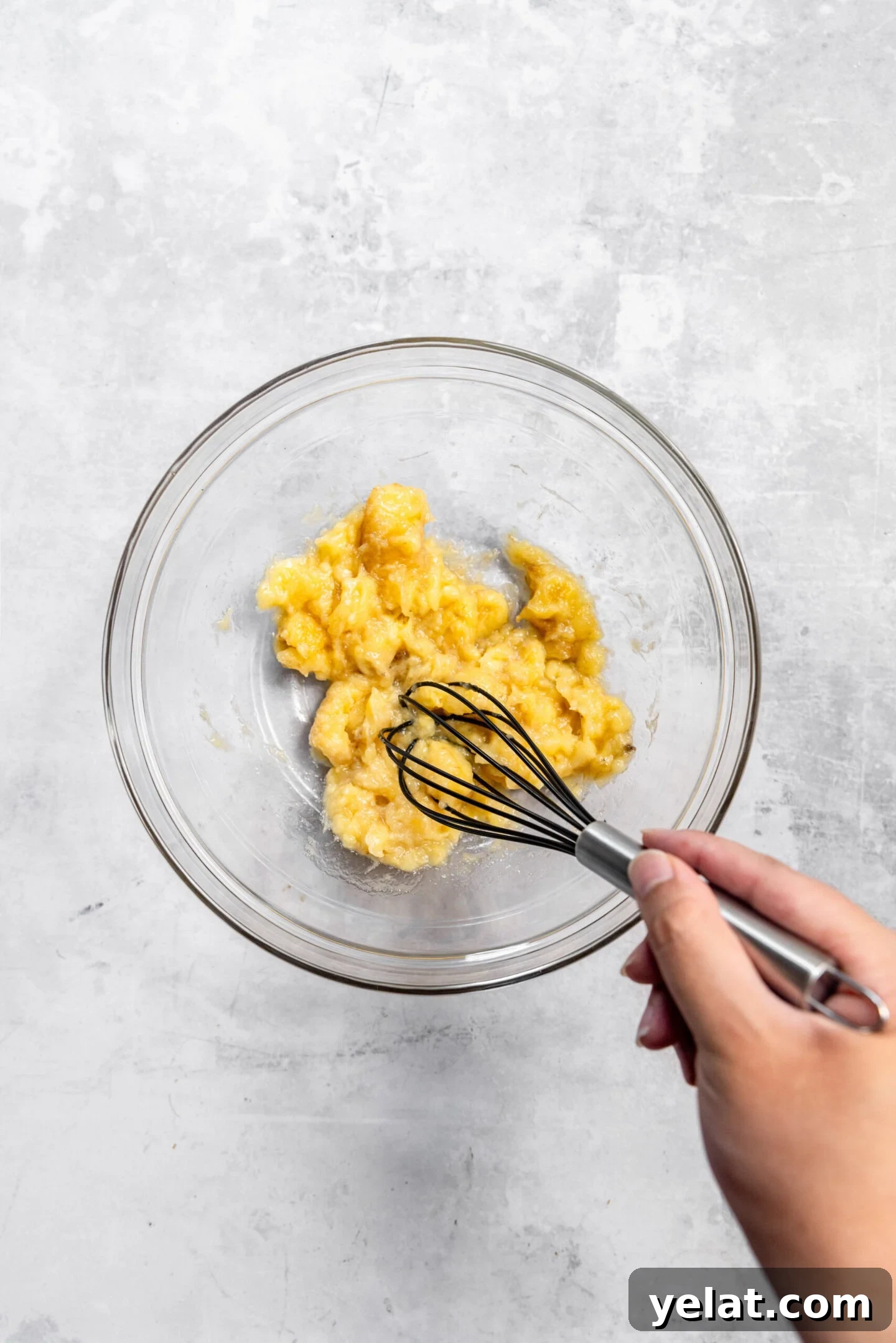 Moist Small-Batch Banana Muffins Recipe for Perfect Breakfast 5 Bananas being mashed by a whisk in a mixing bowl