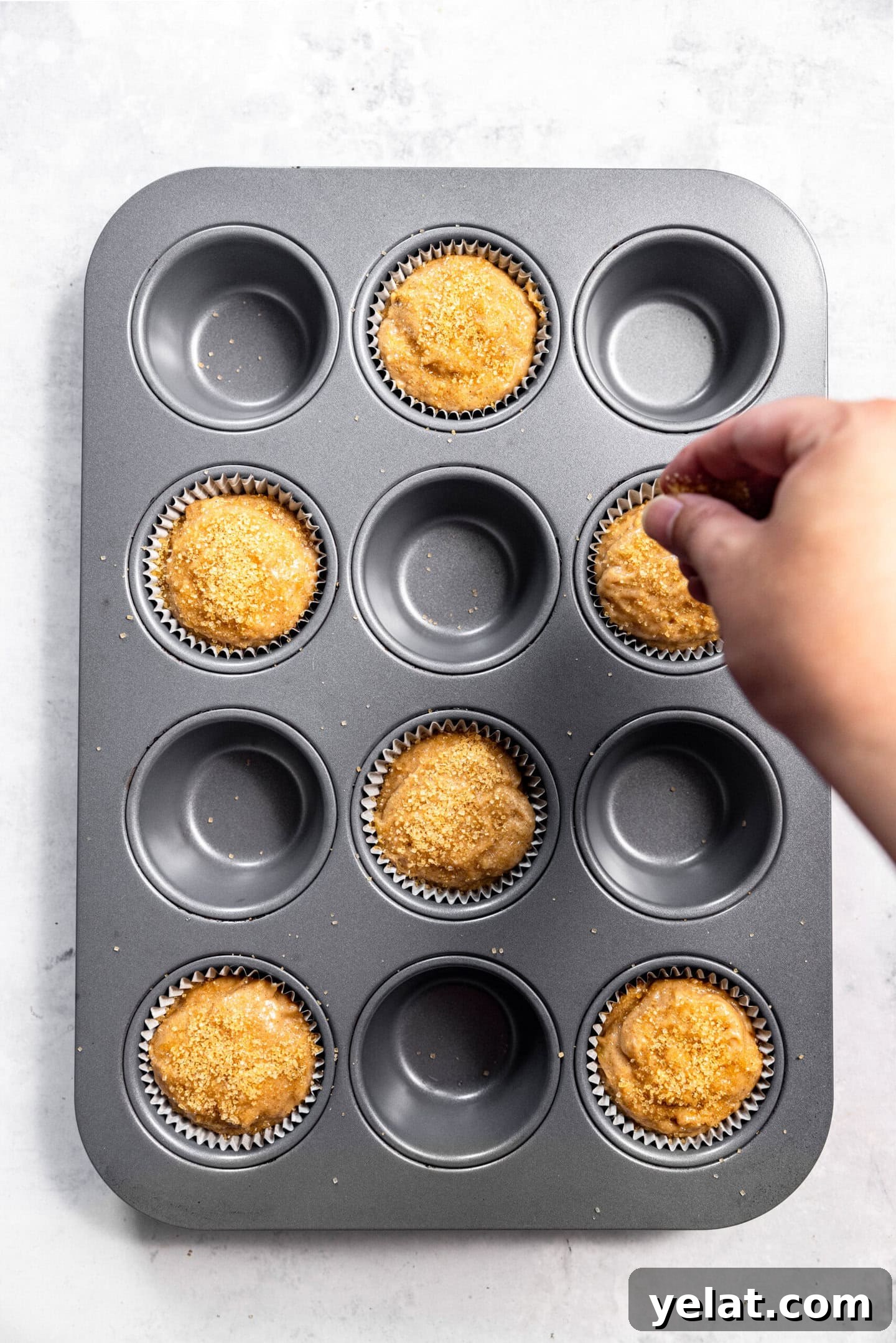 Moist Small-Batch Banana Muffins Recipe for Perfect Breakfast 10 Turbinado sugar being sprinkled on top of muffin batter