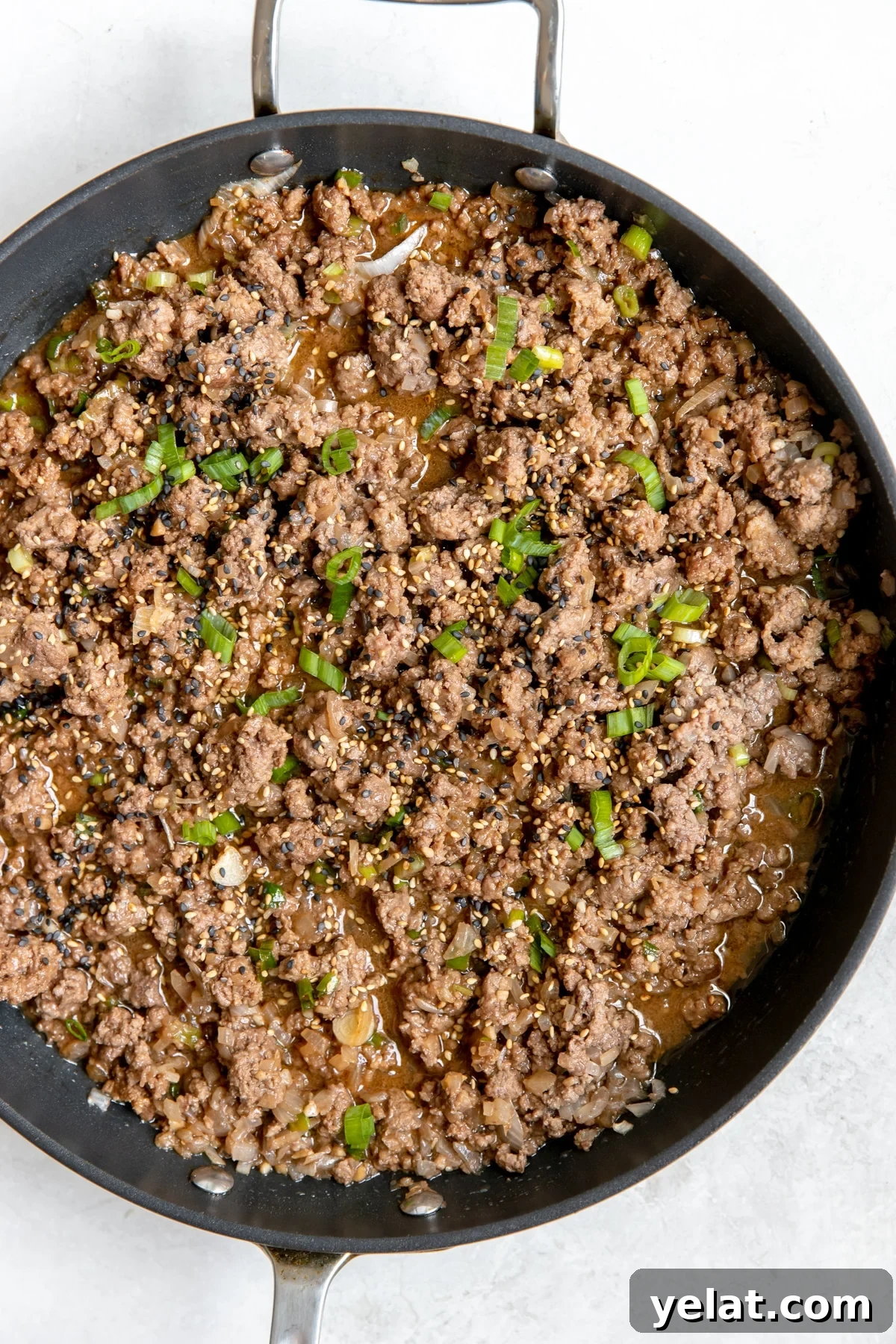 Asian-Style Beef and Noodles Stir-Fry Recipe 3 ground beef in a large black skillet with green onions on top