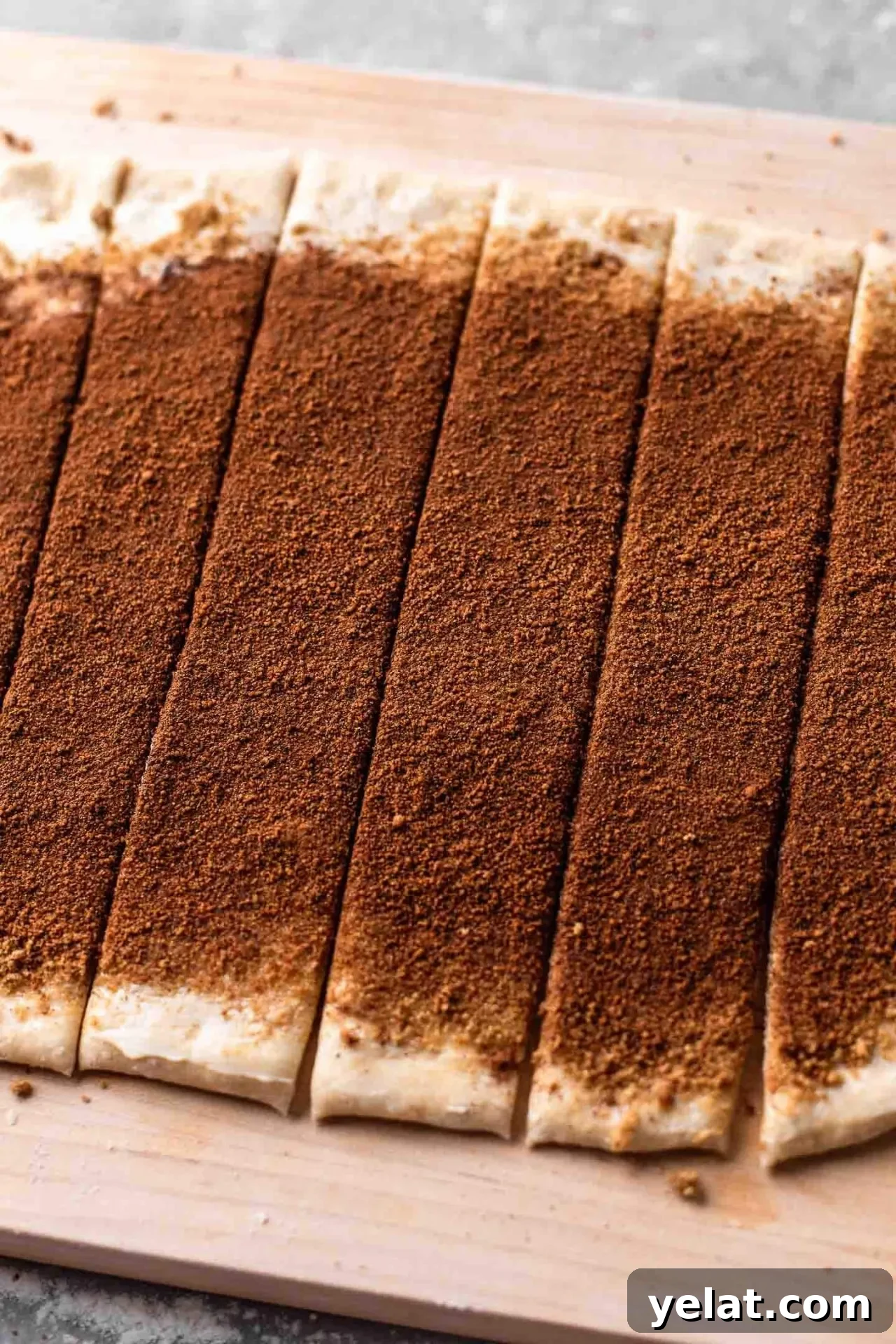 Cinnamon Rolls for Two: Small-Batch Recipe for Soft, Gooey Treats 3 small batch cinnamon rolls rolled out dough topped with sugar and cinnamon and cut into strips