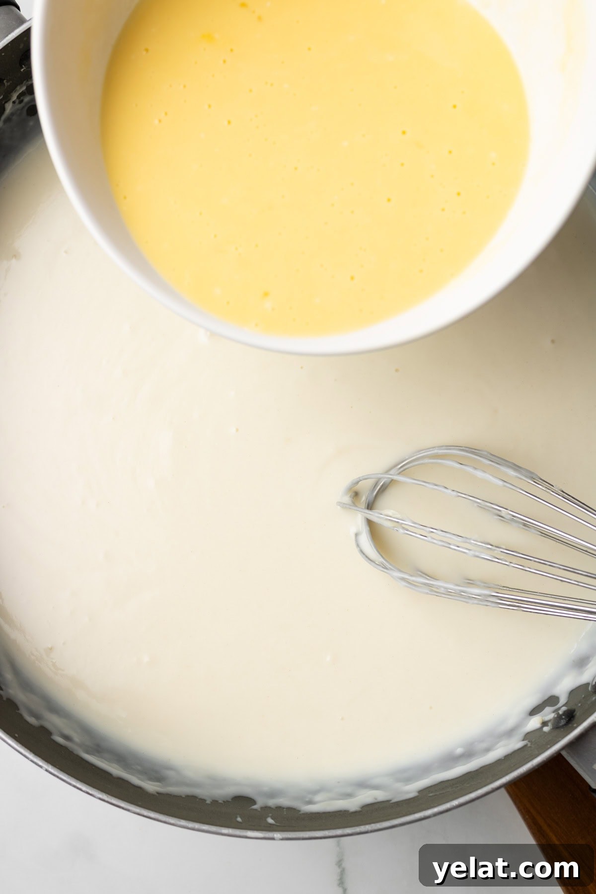 An overhead image of adding the egg mixture to the bechamel sauce.