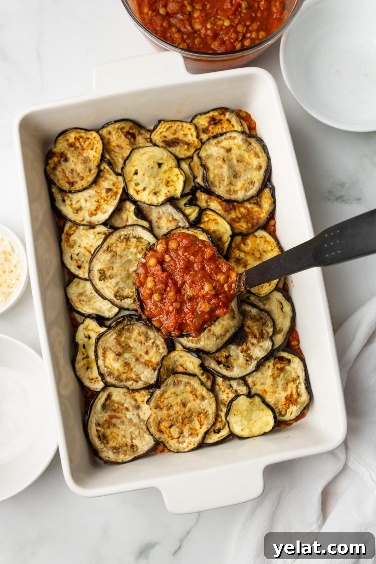 An overhead image of layering the eggplants and potato slices on the baking dish.