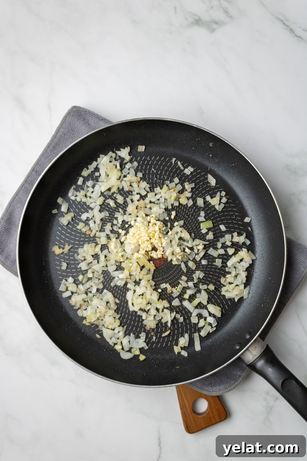 An overhead image of sauteing onions and garlic on a saucepan.