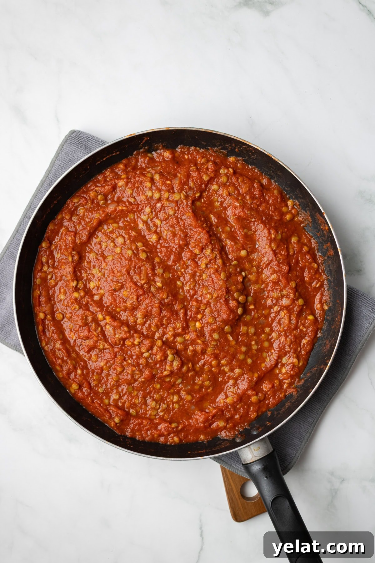 An overhead image of adding tomatoes and lentils on the saucepan.