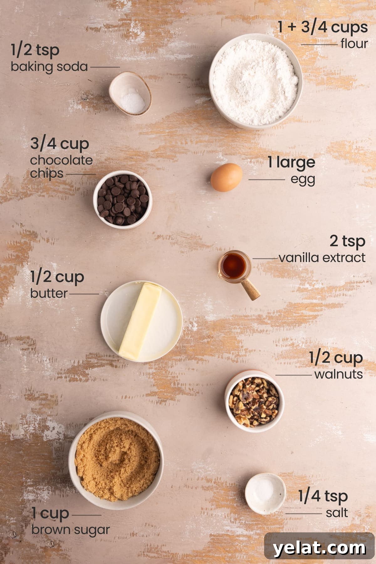 All ingredients needed for chocolate chip walnut cookies including flour, baking soda, egg, chocolate chips, vanilla extract, butter, walnuts, brown sugar, and salt. 