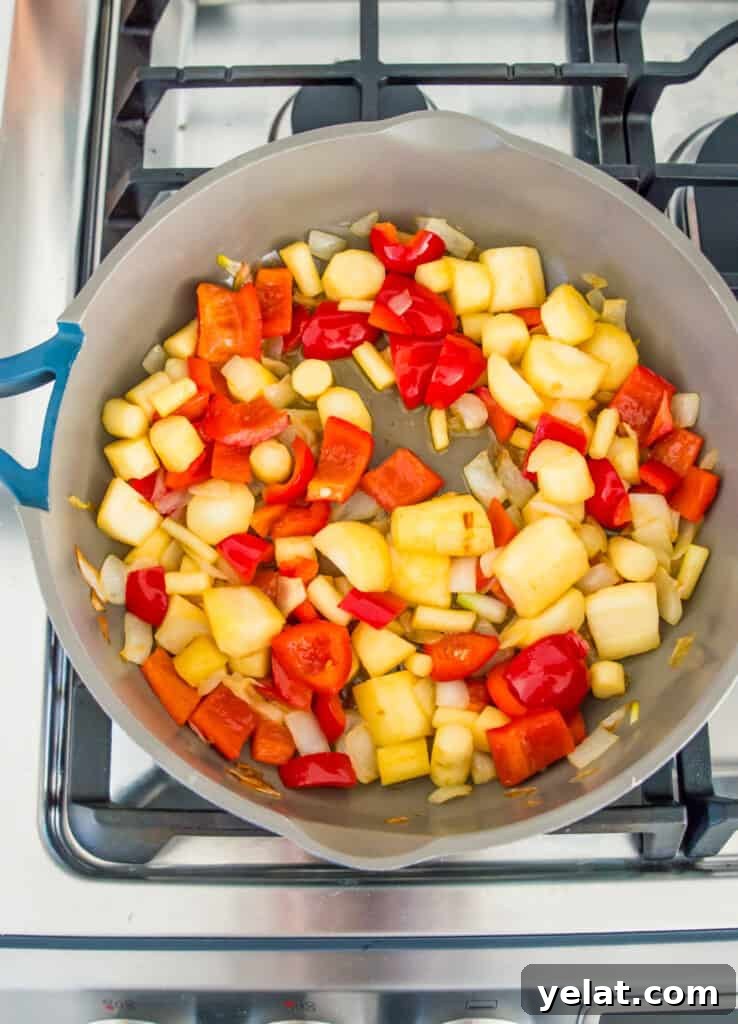 Roasted Red Pepper Cashew-Parsnip Dip (Vegan) 6 A pan on the stovetop with chopped red bell pepper and parsnips cooking in it.