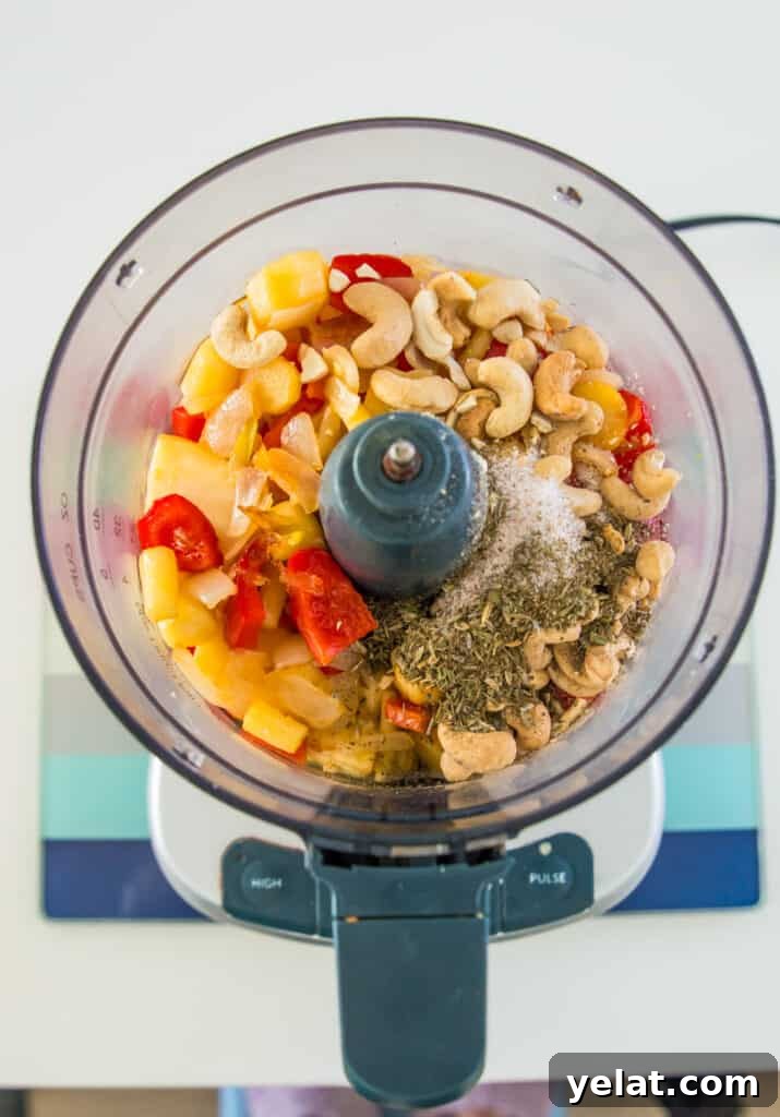 Roasted Red Pepper Cashew-Parsnip Dip (Vegan) 7 A food processor with chopped red bell pepper, parsnips, cashews and spices in it.