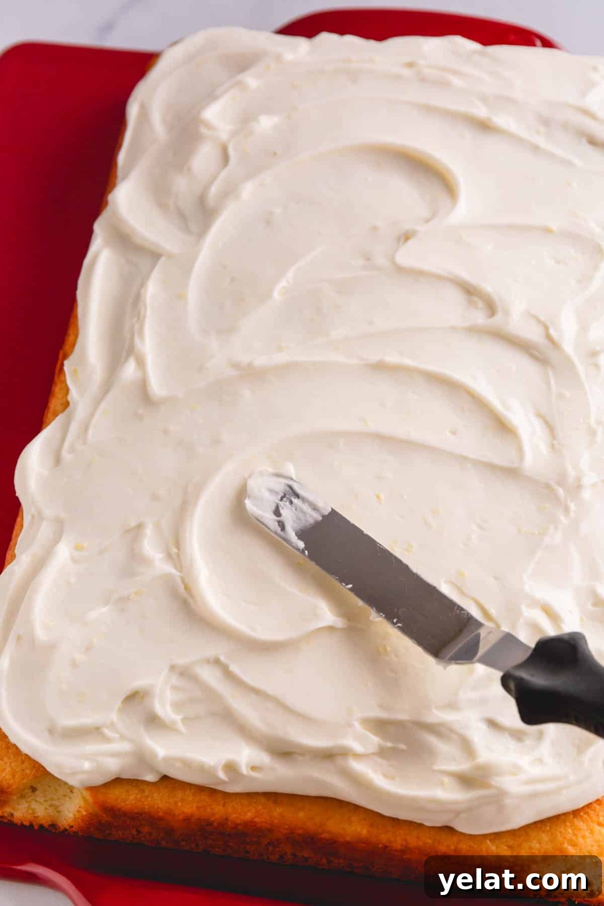 Lemon Sheet Cake Recipe: Zesty, Moist Lemon Cake for Large Groups 11 A lemon sheet cake being frosted with lemon cream cheese frosting.
