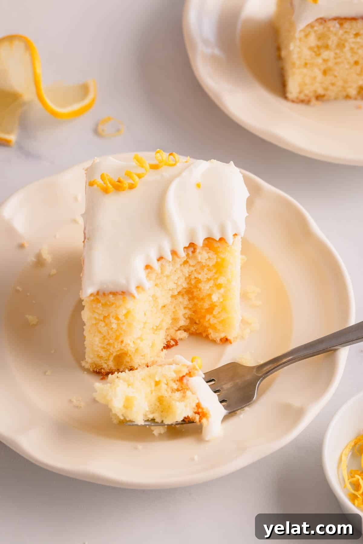 Lemon Sheet Cake Recipe: Zesty, Moist Lemon Cake for Large Groups 13 A slice of frosted lemon sheet cake on a plate with a fork holding a bite.