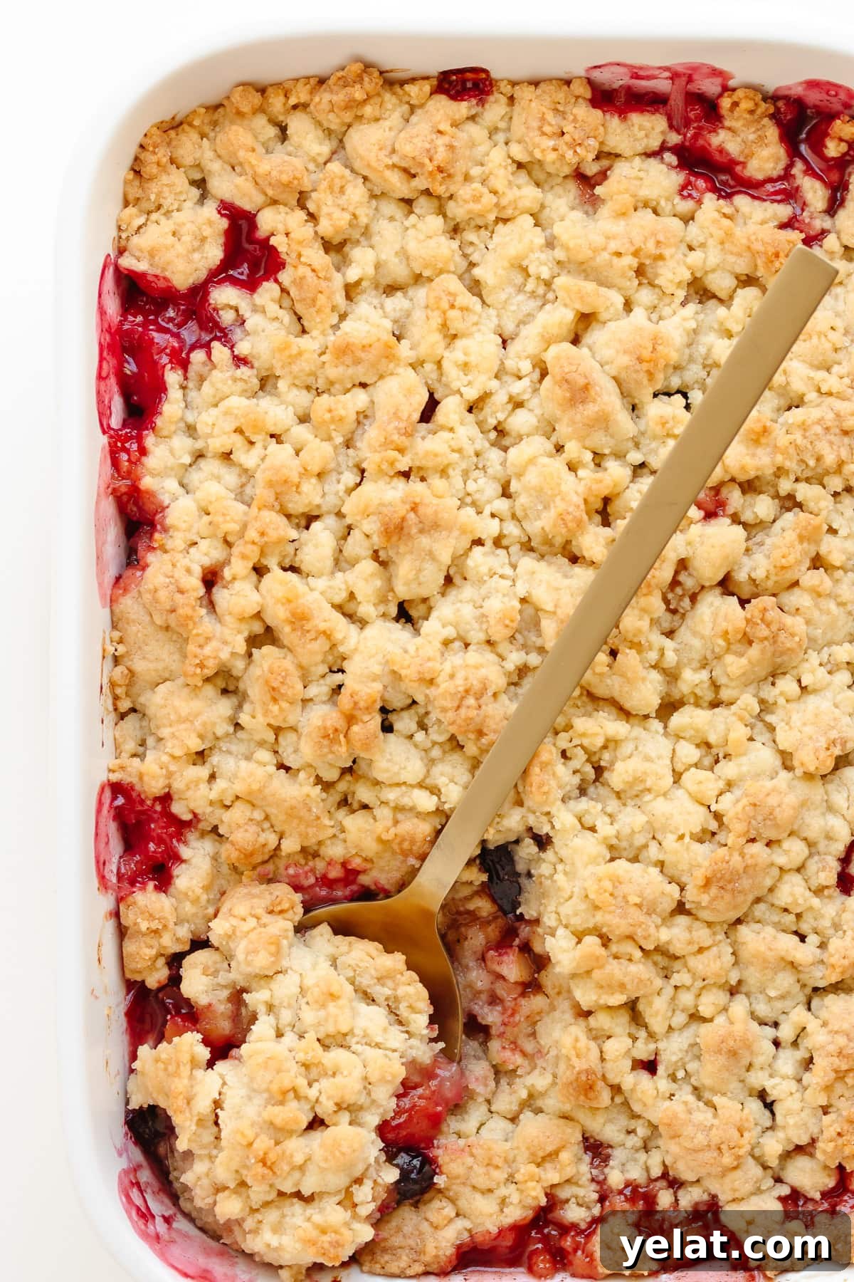 Rustic Plum & Apple Crumble Recipe for Fall Baking 12 Apple and plum crumble in a white baking dish with gold colored serving spoon.
