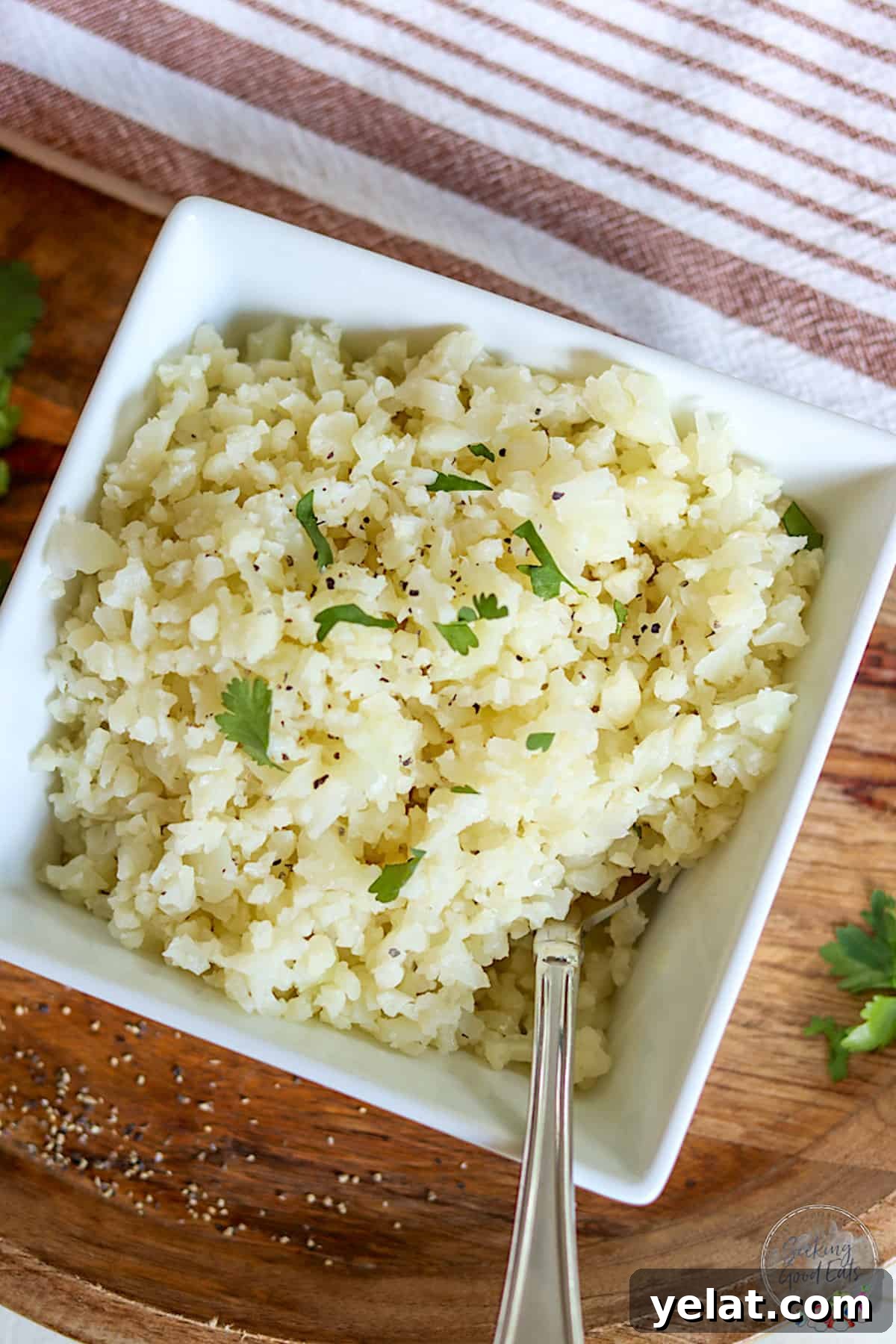 Perfect Riced Cauliflower Recipe for Meal Prep and Sides 2 A square white bowl of cooked riced cauliflower.