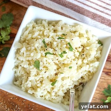 Perfect Riced Cauliflower Recipe for Meal Prep and Sides 4 A white bowl of cooked riced cauliflower garnished with pepper and parsley.