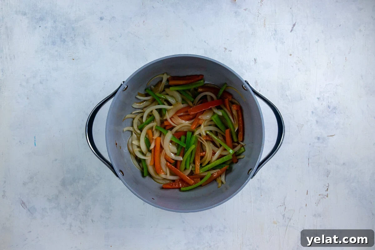 Cajun Sausage Spaghetti Recipe: Spicy Pasta with Andouille 5 Sliced onions and bell peppers sauteed in a pot.