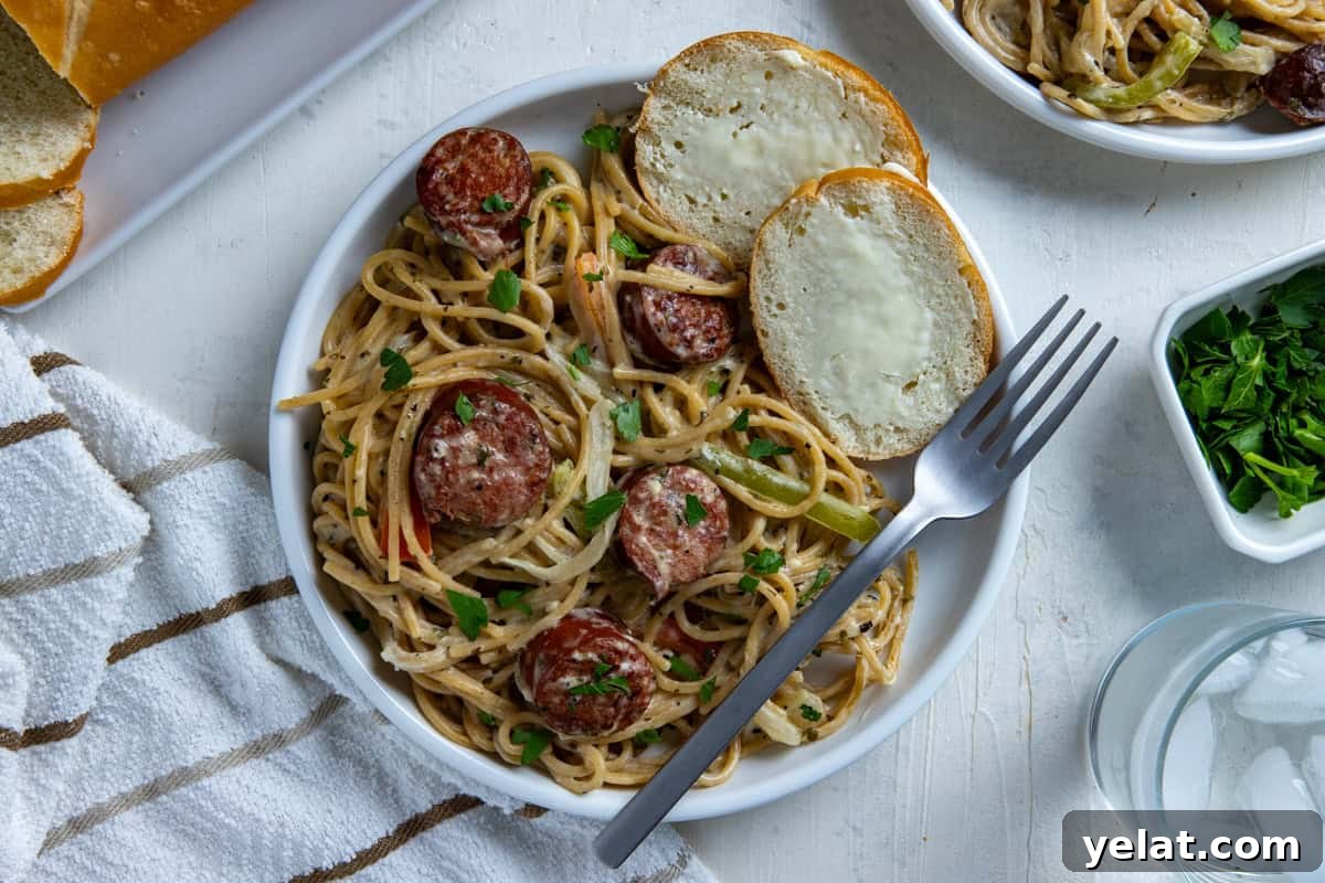 Cajun Sausage Spaghetti Recipe: Spicy Pasta with Andouille 8 Cooked cajun sausage spaghetti on white plate with a fork and two slices of buttered French bread on the side.
