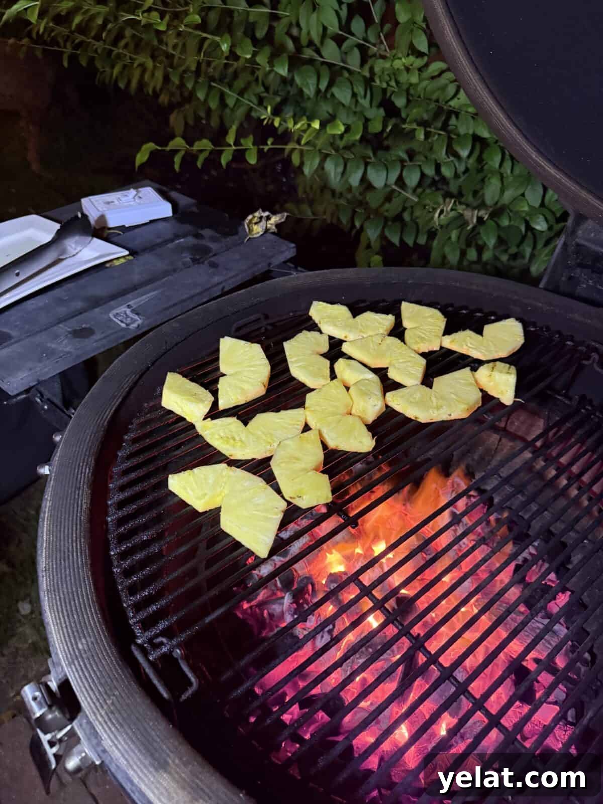 Pineapple slices grilling over hot coals, caramelizing.