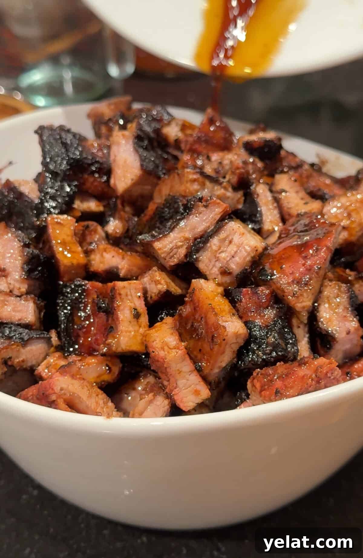 A bowl filled with chopped, grilled meat pieces with sauce.