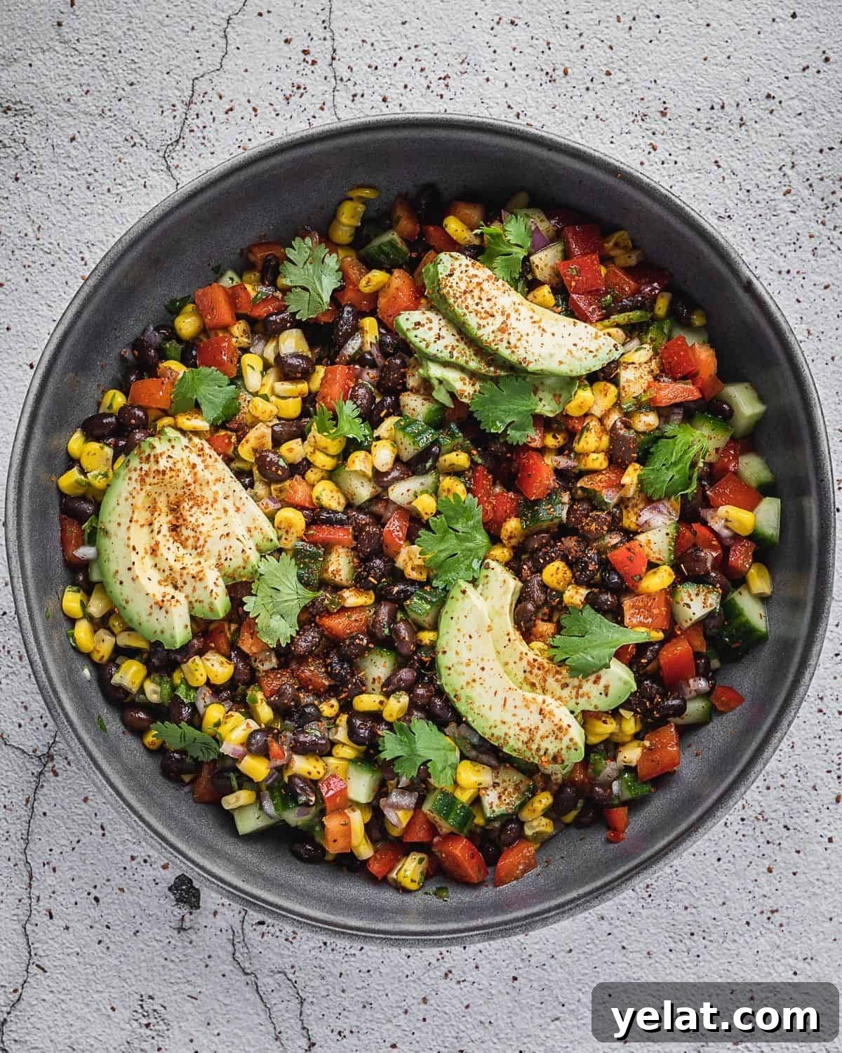 Fiesta salad with corn, beans, peppers and cilantro in a bowl with avocado.