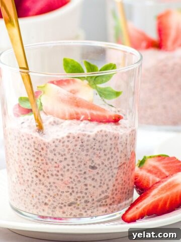 A vase of strawberry chia pudding topped with fresh strawberries.