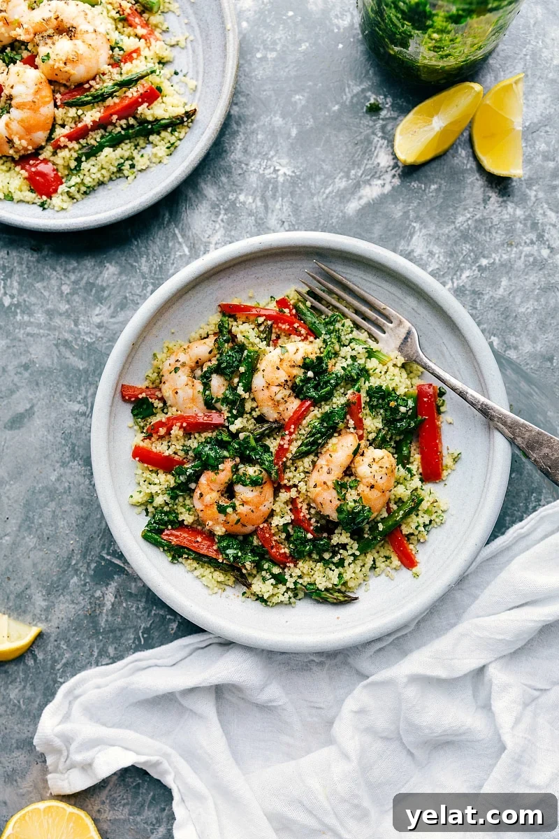 Simple and deliciously seasoned shrimp couscous roasted on a sheet pan with asparagus and red pepper, topped with a green herb sauce. Overhead photo of finished Shrimp Couscous bowls