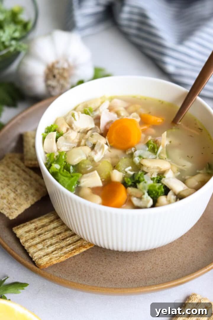 Hearty White Bean and Chicken Soup with Garlic and Herbs 2 small white bowl filled with chicken and white bean soup on a plate with crackers