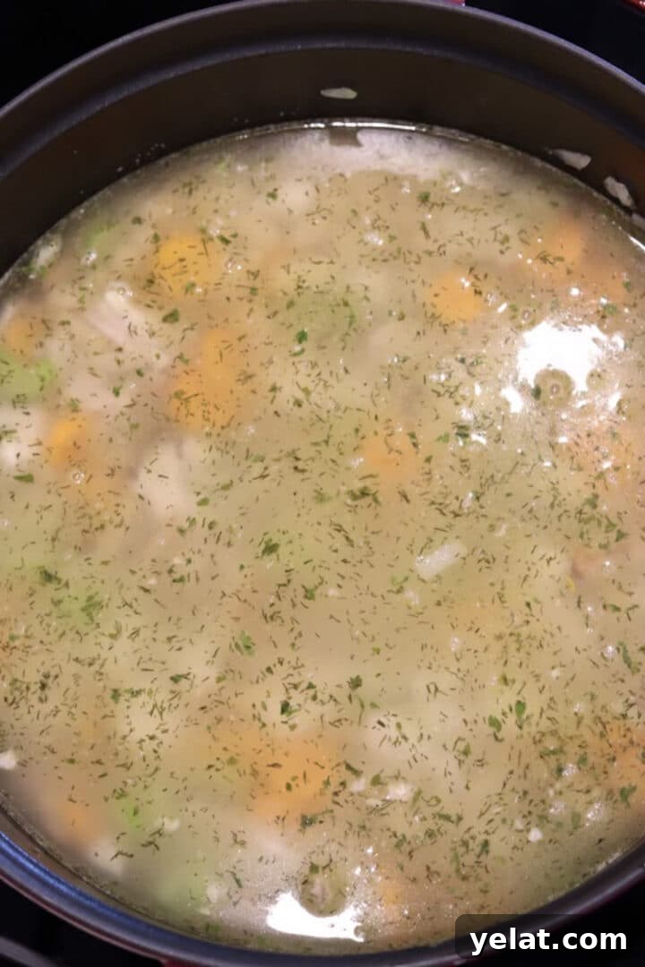 Hearty White Bean and Chicken Soup with Garlic and Herbs 7 Chicken and white bean soup simmering in a large dutch oven