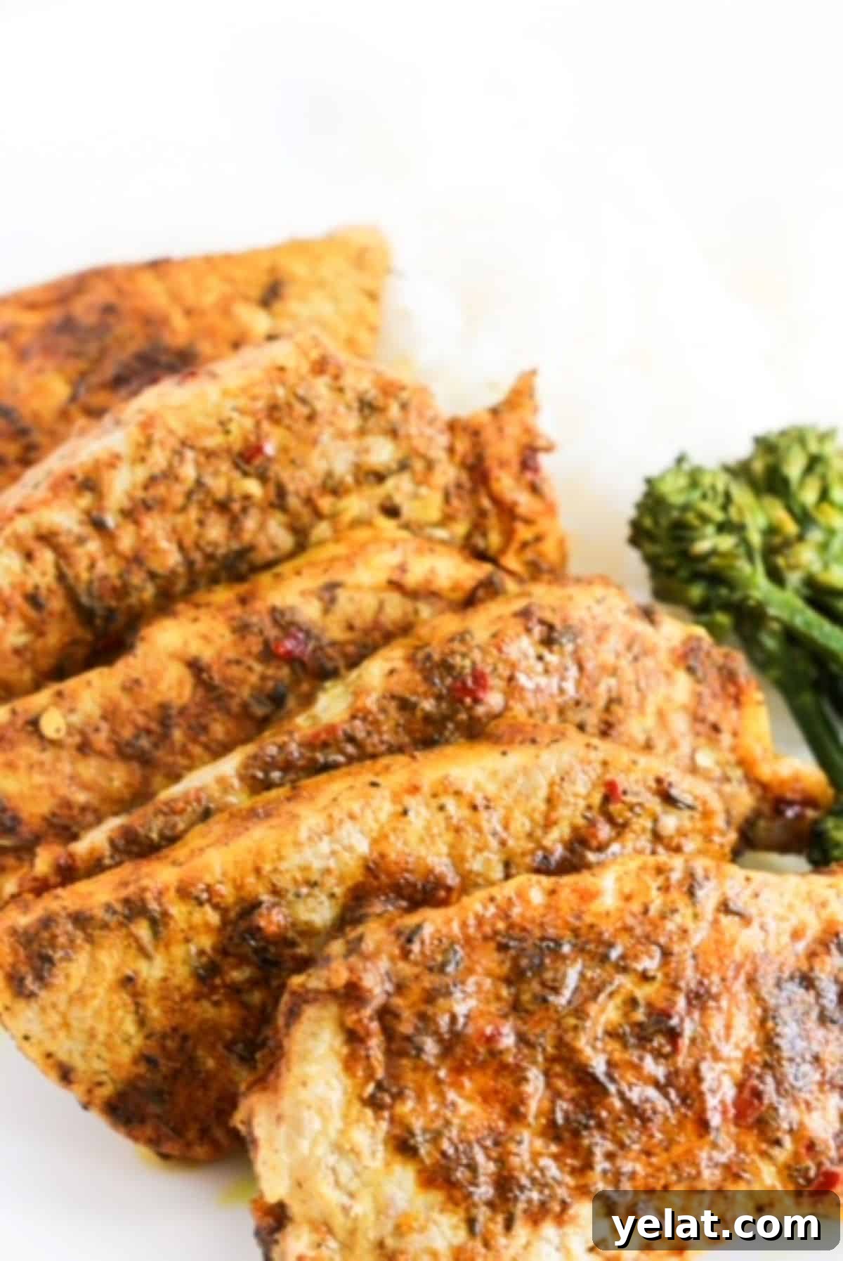 Crispy Oven-Baked Boneless Pork Chops with Garlic Herb Rub 2 Six cooked jerk lime marinated pork chops overlapping each other on a white plate with broccolini to the right.