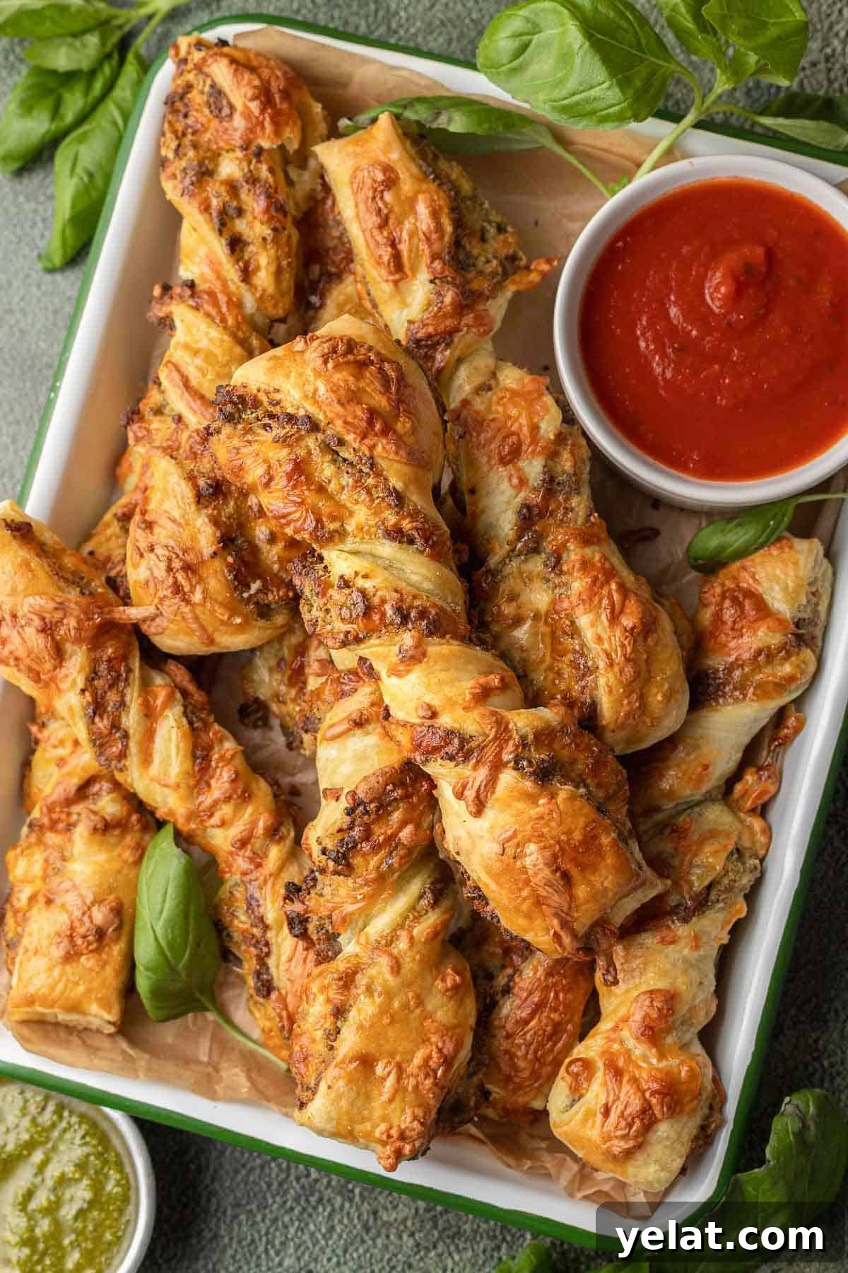Savory Sausage Puff Pastry Twists Recipe for Parties 2 Sausage Pesto Twists on tray with marinara in a cup.