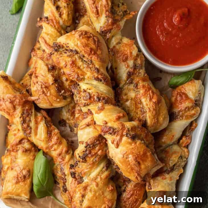 Sausage Pesto Twists on tray with marinara in a cup.