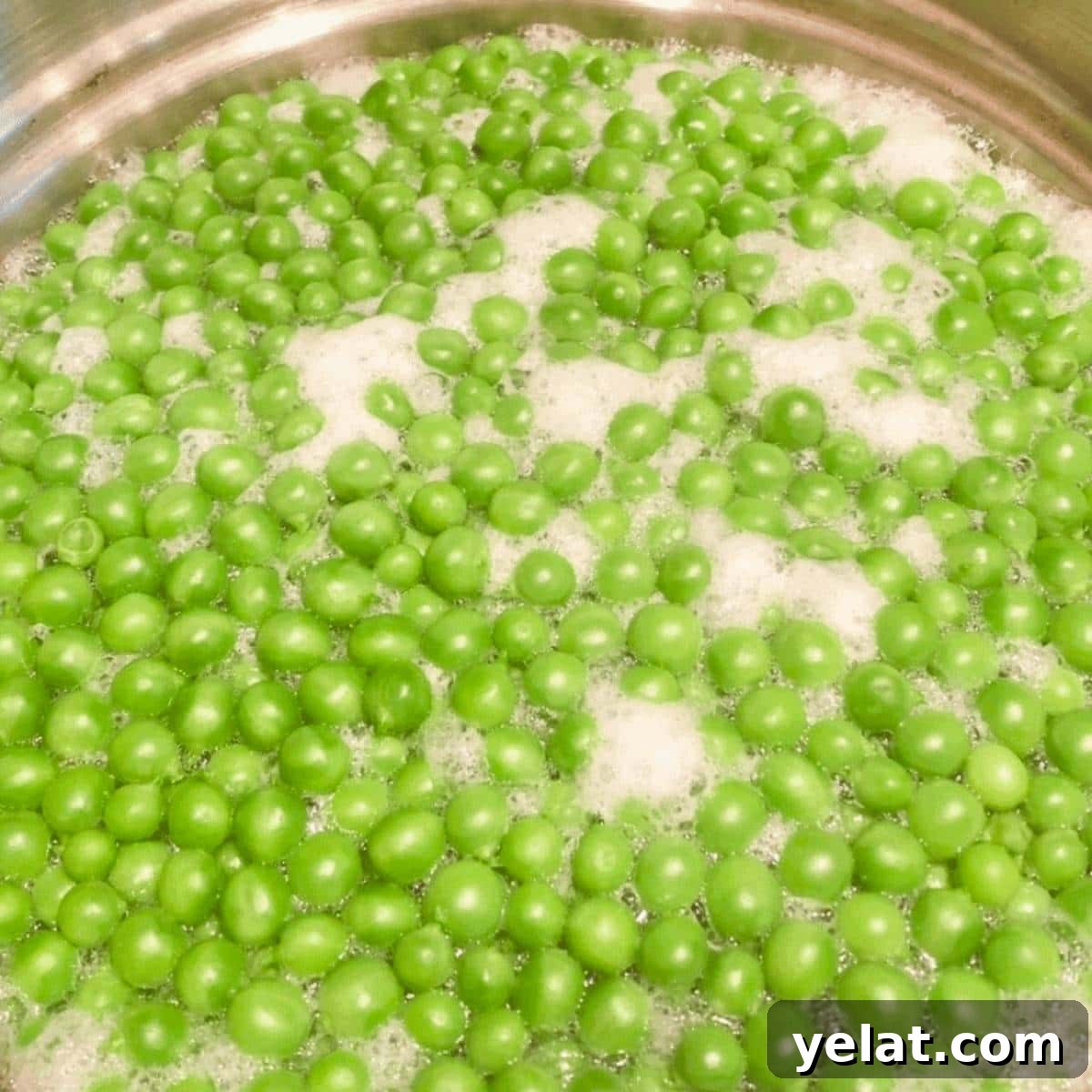Peas boiling in a large pot of boiling water.