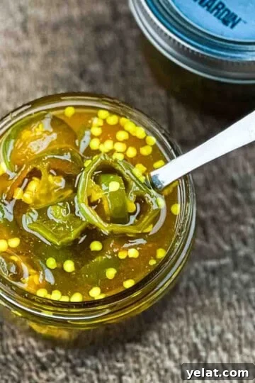An open jar of cowboy candy with a spoon in it.