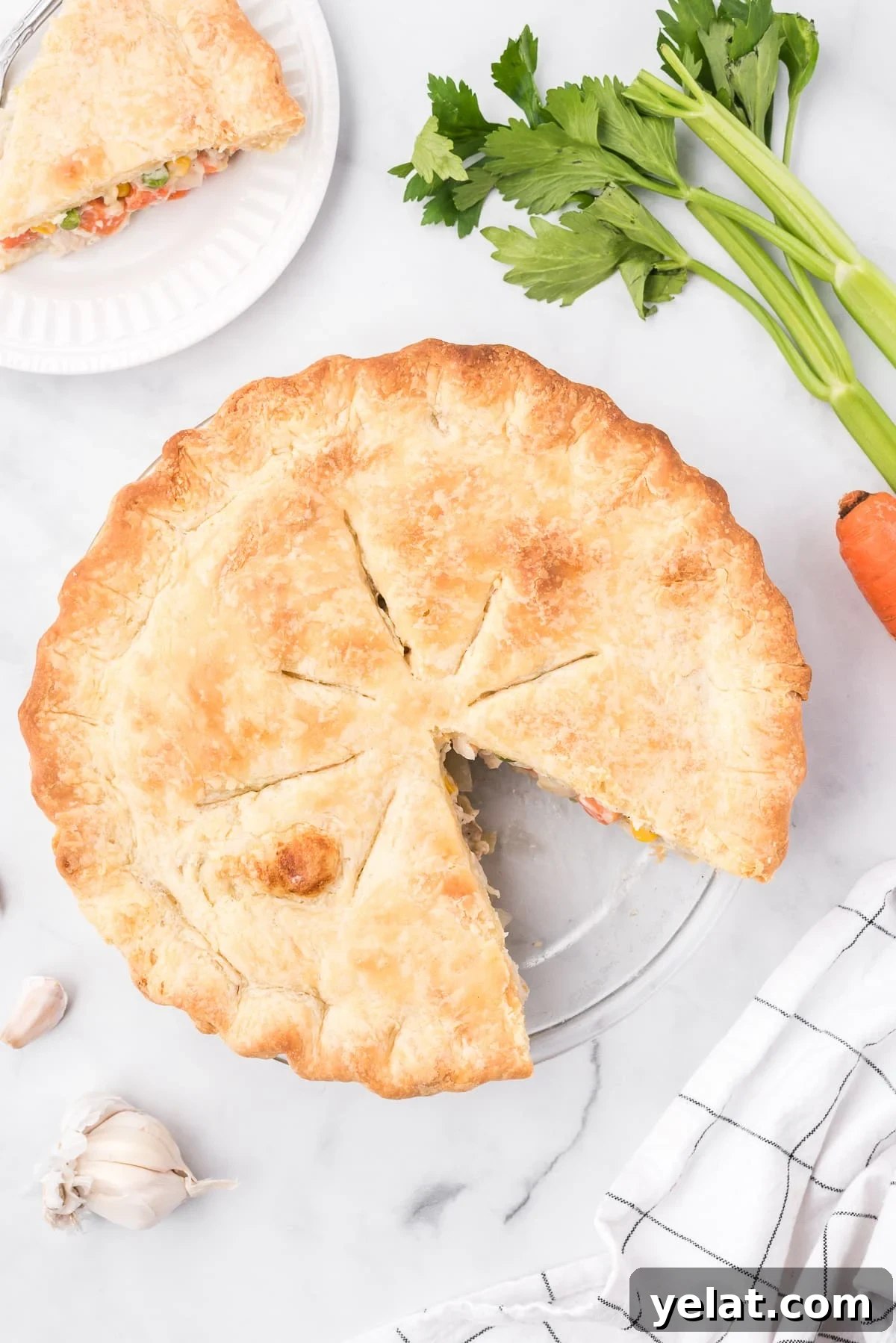 Overhead image of a chicken pot pie in a pie dish with one single slice removed.